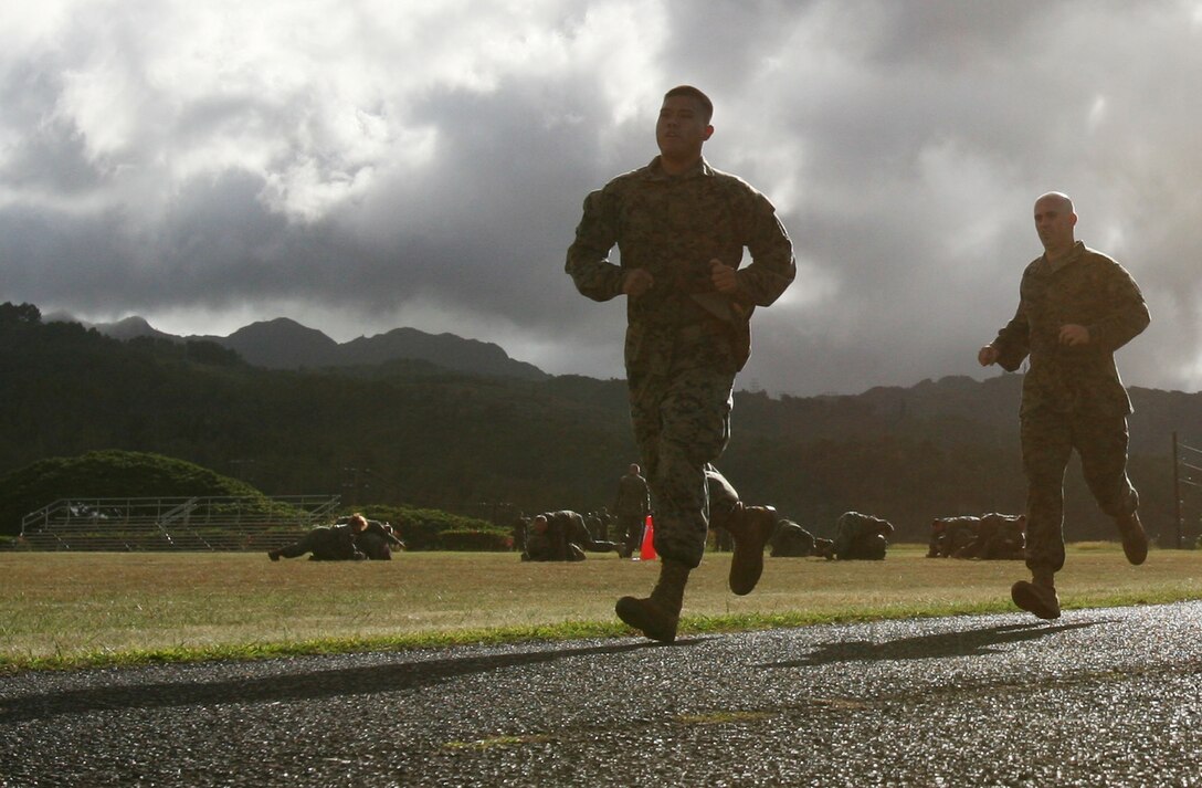 U.S. Marine Corps Forces, Pacific Marines run a practice the 880-yard run around the track while fellow Marines perform spin drills in the infield during combat fitness test training at Bordelon Field Oct 17. ::r::::n::Progressing into week three of a five-week training schedule, Headquarters and Service Battalion Marines face an eight-station course performing exercises consisting of martial arts, upper and lower body conditioning and stretching.::r::::n::The mandated training, conducted each Friday in October by the training section, incorporates CFT events as well as traditional Corps training.  ::r::::n::"It's a wide variety of exercises encompassing the total body package, which is designed to test you in ways that are unorthodox," said Sgt. Robert Manion, nuclear, biological and chemical chief for H&S Battalion, MarForPac. ::r::::n::Already half way through the training, MarForPac still has two weeks until completion.::r::::n::Manion said he feels the Marines are progressing through the training and improving their agility and stamina as well as motivation and esprit de corp. ::r::::n::