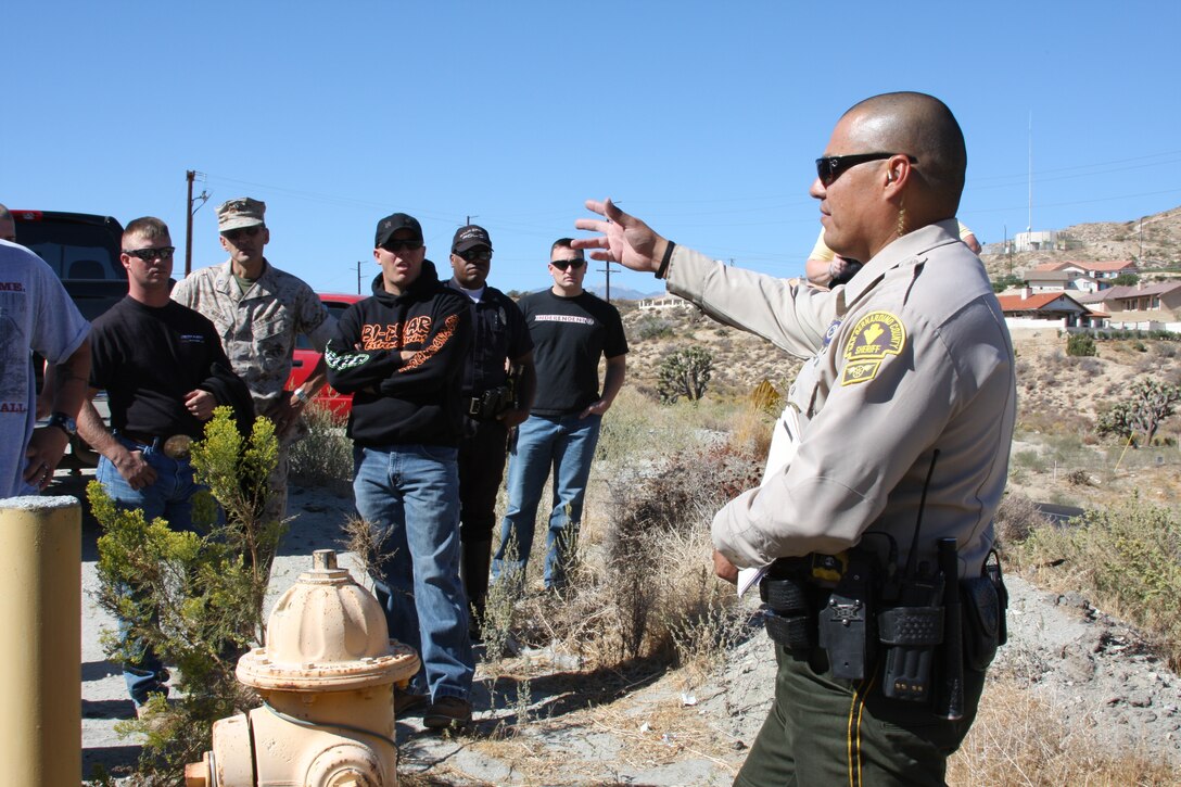 Officer Raymond Camacho, traffic motor officer and a member of the major accident investigation team with the San Bernardino County Sheriff’s Department, talks to more than 30 Combat Center motorcycle riders about the importance of being safe while riding during a motorcycle safety brief Oct. 17, while standing where they found the destroyed motorcycle of a Marine who was killed after he lost control and ran off the road. His motorcycle was found more than 240 feet away from initial impact.