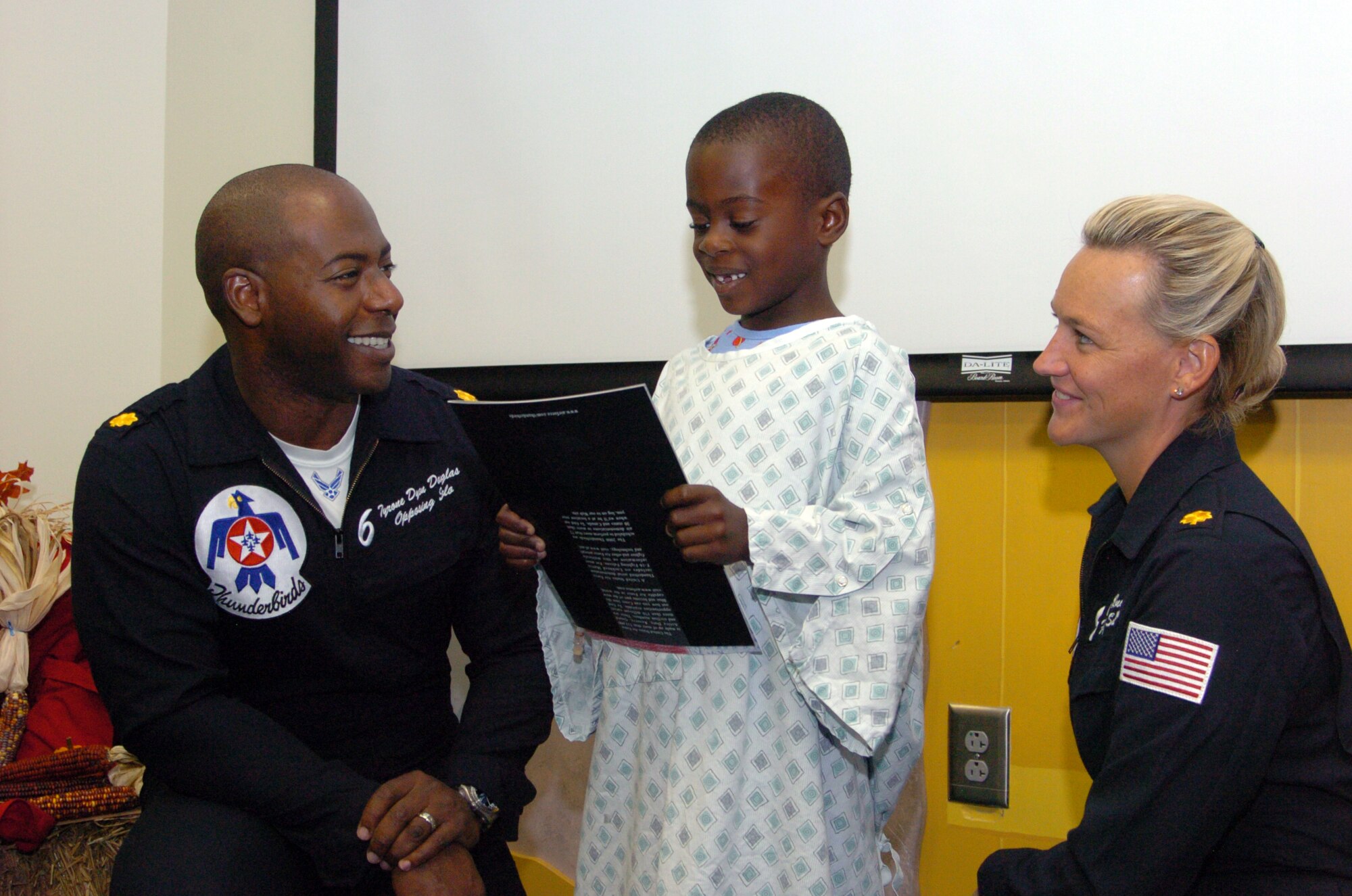 Jordan Headley, age 5, is all smiles after receiving a 2008 Thunderbirds Program from Maj. Tyrone Douglas, USAF Thunderbirds No. 6 F-16 pilot (left), and Maj. Charla Quayle, USAF Thunderbirds flight surgeon (right), at the Children's Healthcare of Atlanta Pediatric Hospital.  "We enjoy the opportunity to have a one-on-one  visit with children," said Maj. Quayle. "It inspires and empowers them to follow their dreams." Thunderbird team members also visited two metro Atlanta area high schools as part of their community relations visits in connection with their appearance at the Wings over Marietta Air Show and Open House at Dobbins ARB, Oct. 18-19. (U.S. Air Force photo/Master Sgt. Stan Coleman)