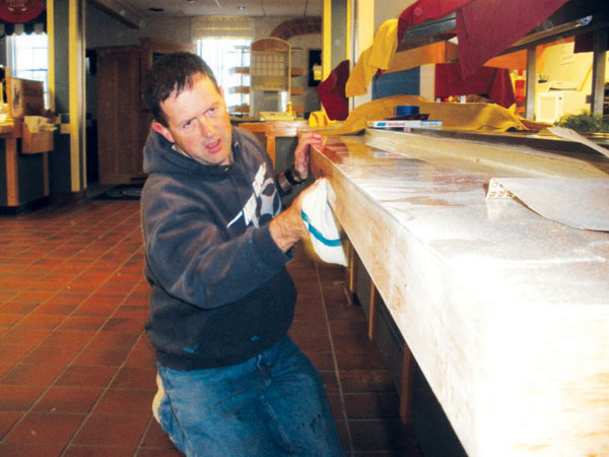 Master Sgt. Ronald Detillion, 90th FSS, cleans a bar to ready for the inspection. Along with the dining facility staff, 90th Civil Engineer Squadron members helped with minor repairs and touch-ups to make the facility look its best. (Photo by Col. Kathleen Cook.)