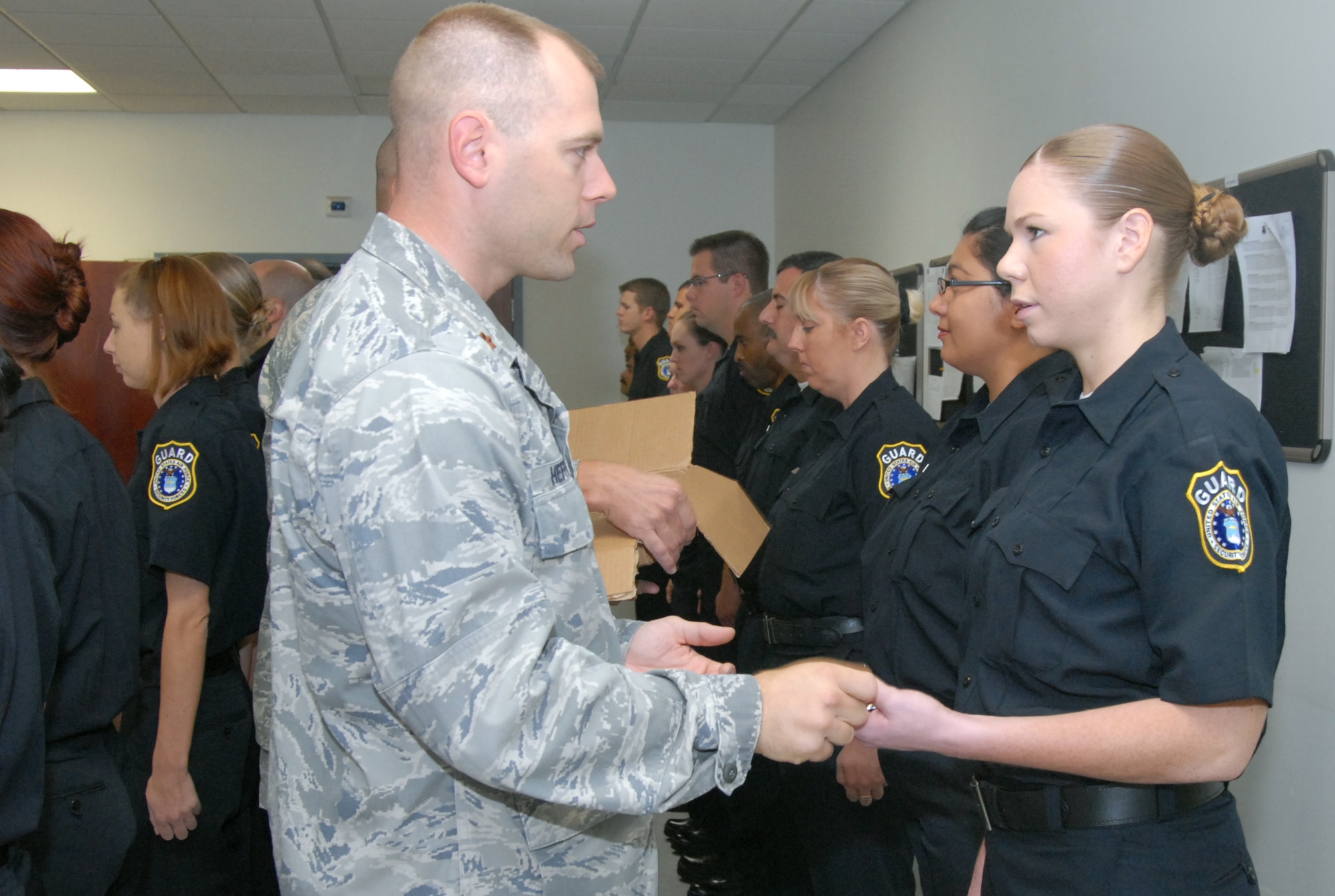 Maj. Steven Heffington, 95th Security Forces Squadron commander, gives a police badge to Andrea Vermillion, civilian security guard, during a ceremony at the 95th SFS headquarters Oct. 9. (Air Force photo by Senior Airman Julius Delos Reyes)