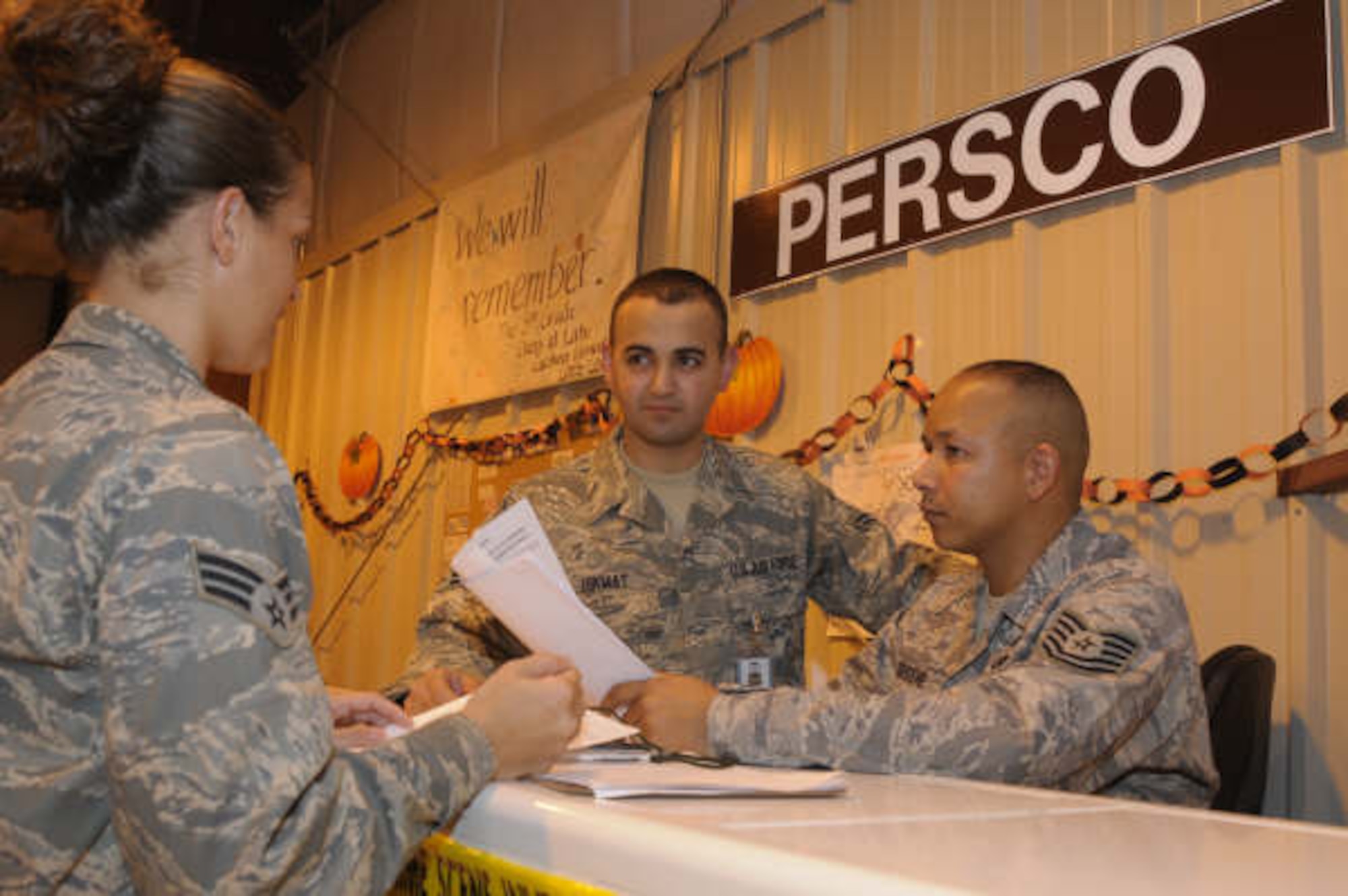 HANSCOM AFB, Mass. – Tech. Sgt. Jamil Greene (right) and Airman First Class Zana Hikmat (center), discuss the Personnel Support for Contingency Operations process with a newly assigned Airman at a deployed location. Sergeant Greene and Airman Hikmat are deployed from the 66th Mission Support Squadron at Hanscom. (U.S. Air Force photo by Mark Wyatt)