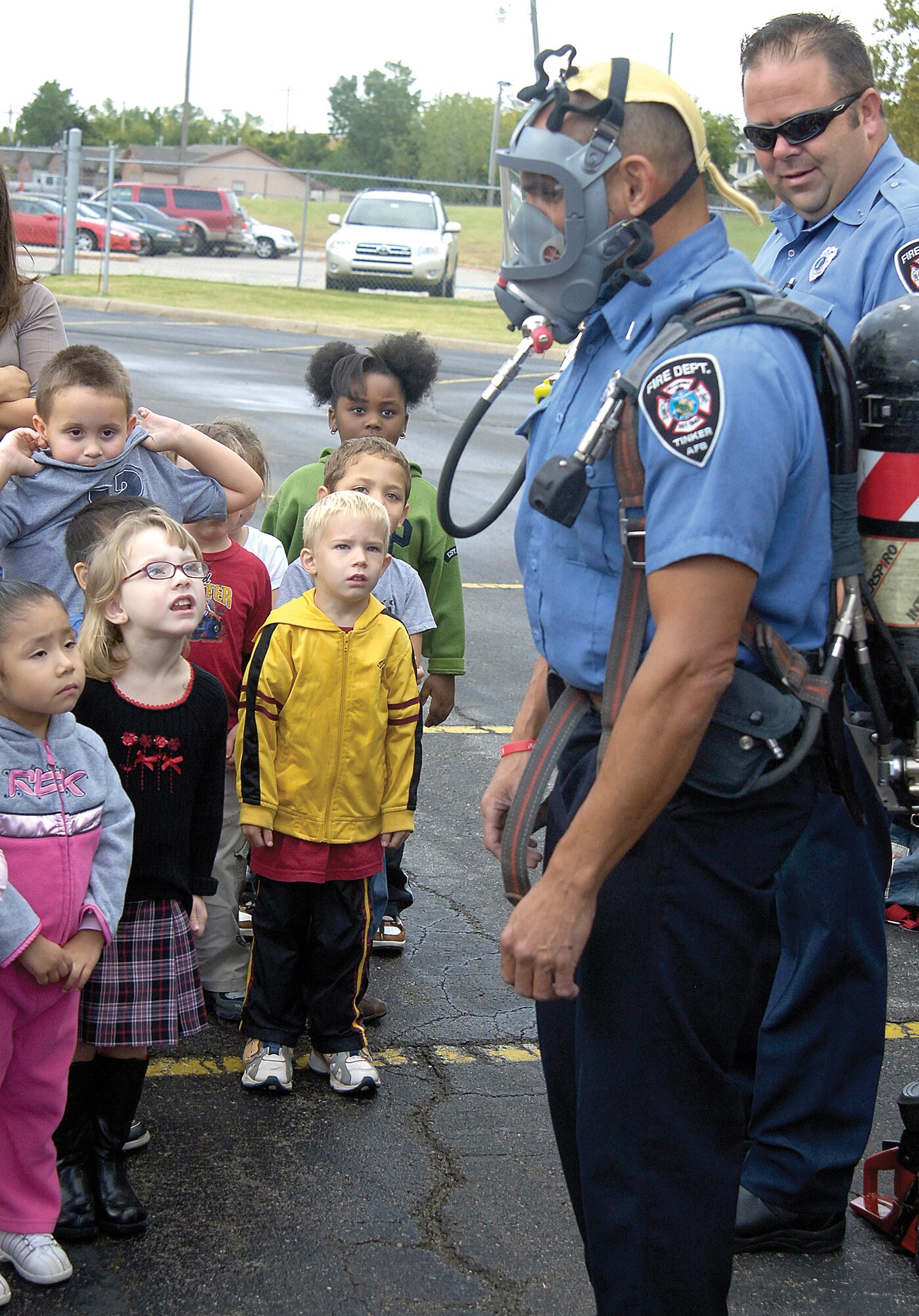 During Fire Prevention Week Oct.4 -10, Tinker firefighters took their lessons on the road to the Tinker Elementary School, the Child Development Centers and various buildings on base. Teaching children not to fear firefighters wearing their voice-distorting oxygen masks or protective gear, Tinker firefighters Kevin Smith, back, and Dominic Hagen show Tinker Elementary students what to expect if firefighters came to rescue them. (Air Force photo/Margo Wright)