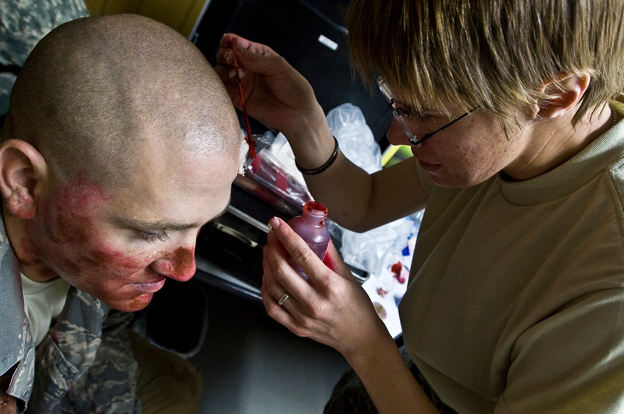 ALI BASE, Iraq -- Staff Sgt. Erin Ward, 407th Expeditionary Medical Squadron, applies fake blood to an Airman to play a wounded victim Oct. 15, 2008. An indirect fire exercise was held here to test the response of nonmilitary and military members. It also tested skills like self aid buddy care and procedures for identifying UXOs. Ward is deployed from U. S. Air Force Academy's 10th Medical Group in Colorado Springs, Colo. (U.S. Air Force photo/Senior Airman Christopher Griffin)