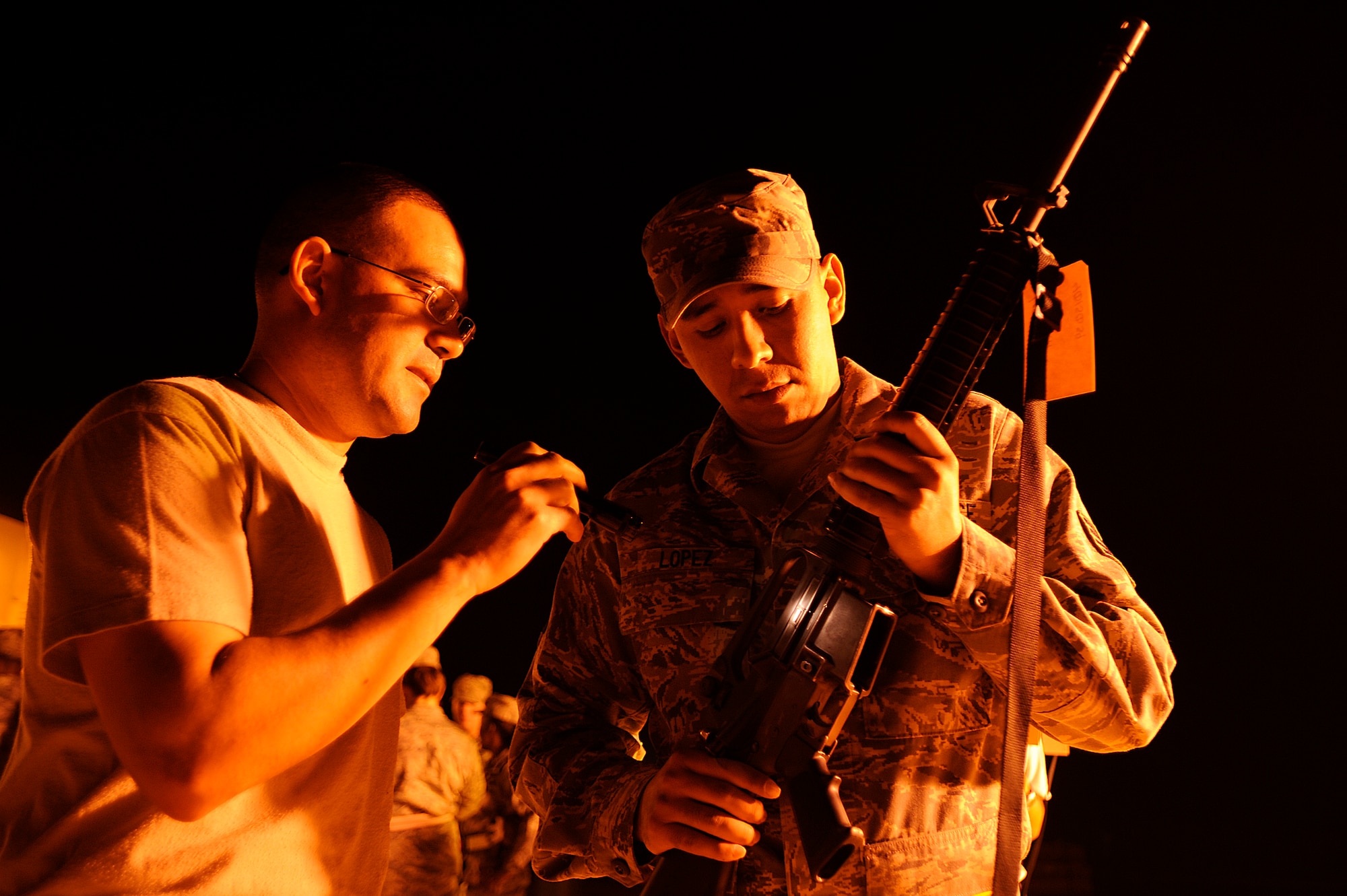 Tech. Sgt. Chris Atkinson shows Staff Sgt. Joseph Lopez the dust cover on his M-16 rifle during a force protection arming drill at Joint Base Balad, Iraq, Oct. 14. The drill is designed to increase Airmen's confidence in weapons handling and force protection procedures by improving individual readiness. Lopez, an accounting liaison technician with the 332nd Air Expeditionary Wing Finance Office, is deployed from Vance Air Force Base, Okla. His hometown is Olustee, Okla. Atkinson, the NCO in charge of customer service with the 332nd Expeditionary Logistics Readiness Squadron, is deployed from McGuire Air Force Base, N.J. His hometown is Harlingen, Texas. (U.S. Air Force photo/Airman 1st Class Jason Epley)