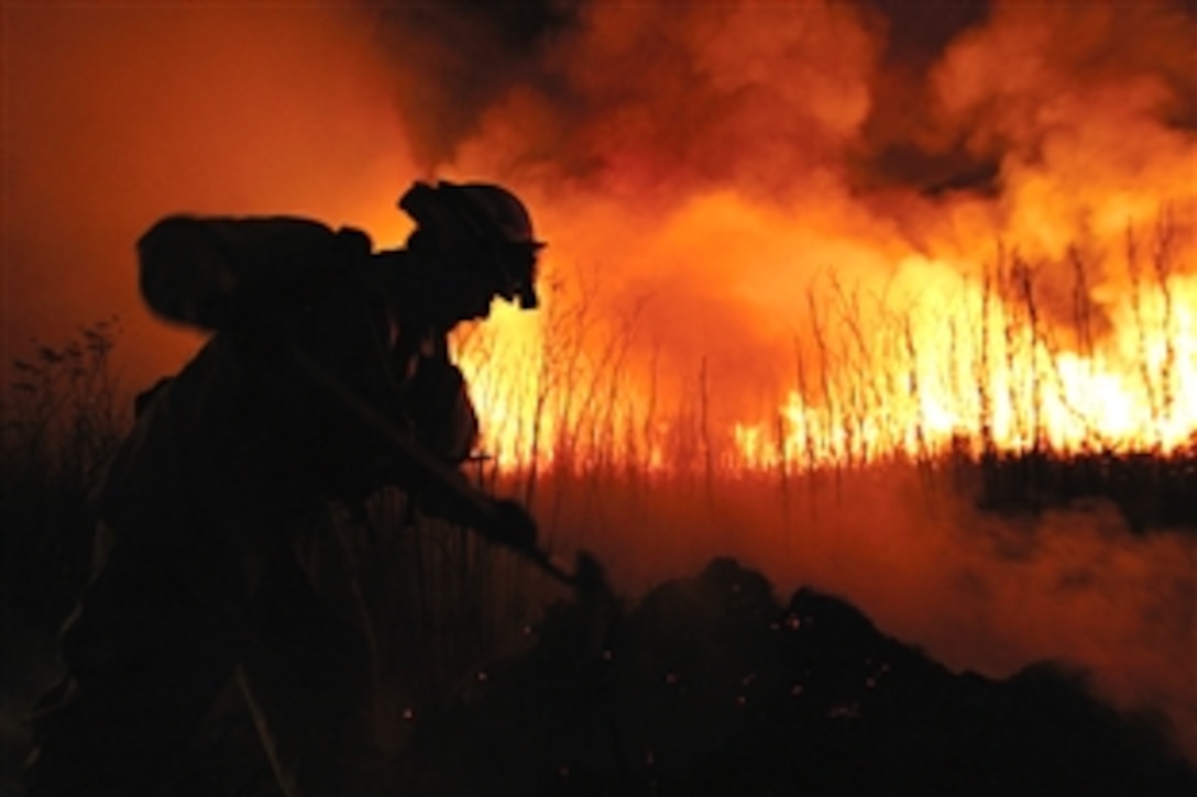 A firefighter from Pendleton’s Fire and Emergency Services digs a trench around charred fields to prevent further damage, Camp Pendleton, Calif., Oct. 8, 2008. More than 670 firefighters on the ground and in the air from across San Diego County worked to extinguish fires on the Marine Corps Base. 
