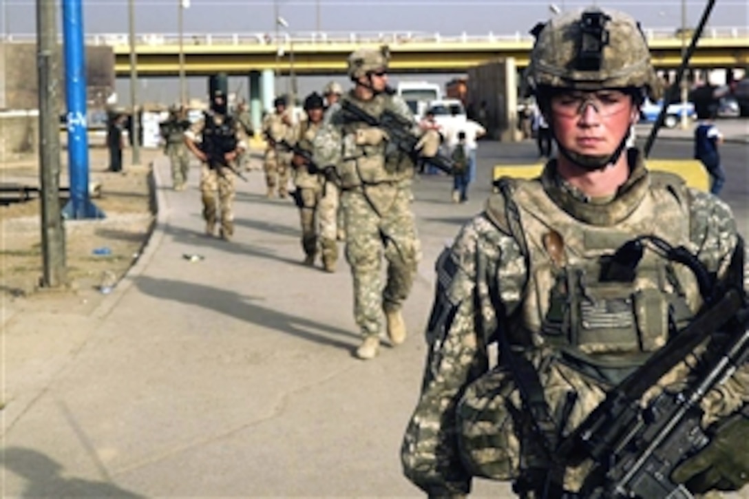 U.S. Army Spc. Travis Grimes and other U.S. and Iraqi soldiers walk along Route Illinois to one of their mission objectives in Muhalla 454 of Shula, Iraq, Oct. 12, 2008. Grimes and other soldiers are assigned to 1st Platoon, Bravo Company, 1st Battalion, 502nd Infantry Regiment, 101st Airborne Division and the Iraqi soldier is a member of Alpha Company, 2nd Battalion, 22nd Iraqi Army Division. 