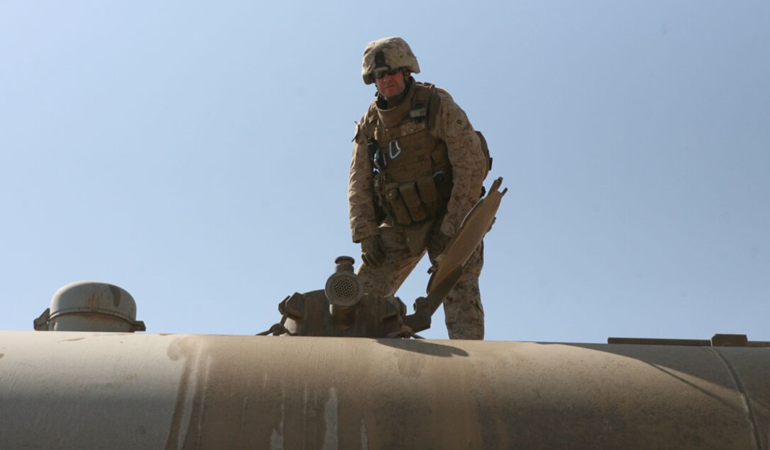 Cpl. Fernando Morales, a machine gunner for Civil Affairs Team 6, Detachment 1, 2nd Battalion, 11th Marine Regiment, Regimental Combat Team 5, stands by a vehicle at the Haqlaniyah, Iraq, Oct. 14. Morales is one of many individual augments now serving in Iraq after being called back to service. Once this deployment is completed, Morales plans on going back to his job and starting school. ::r::::n::