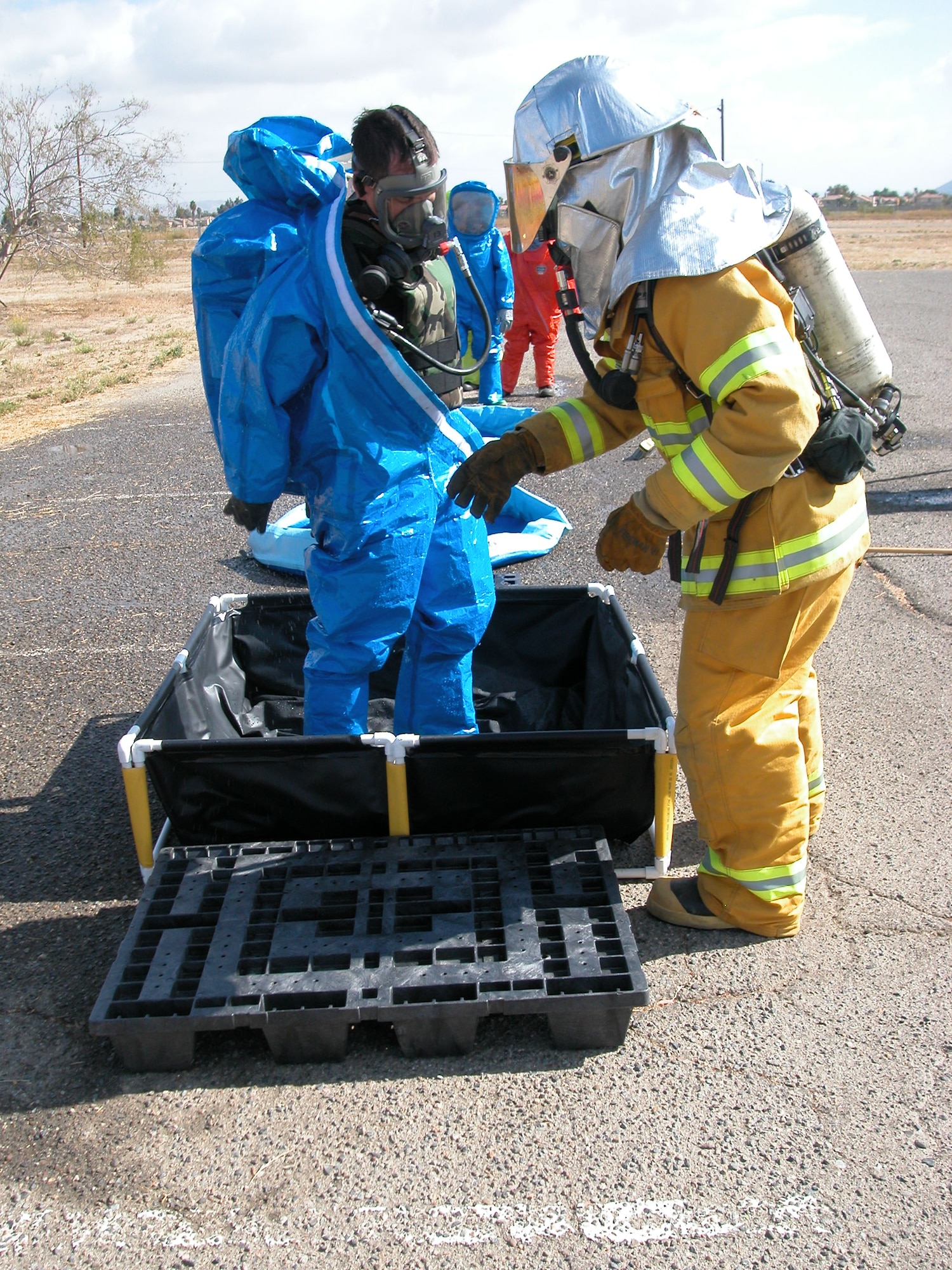 Members of the 452nd Fire Department helps a member of the 452nd CEX Emergency Management remove a “Hazmat” suit after being processed during decontamination operations. (U.S Air Force photo by Senior Airman Kara McGrath)