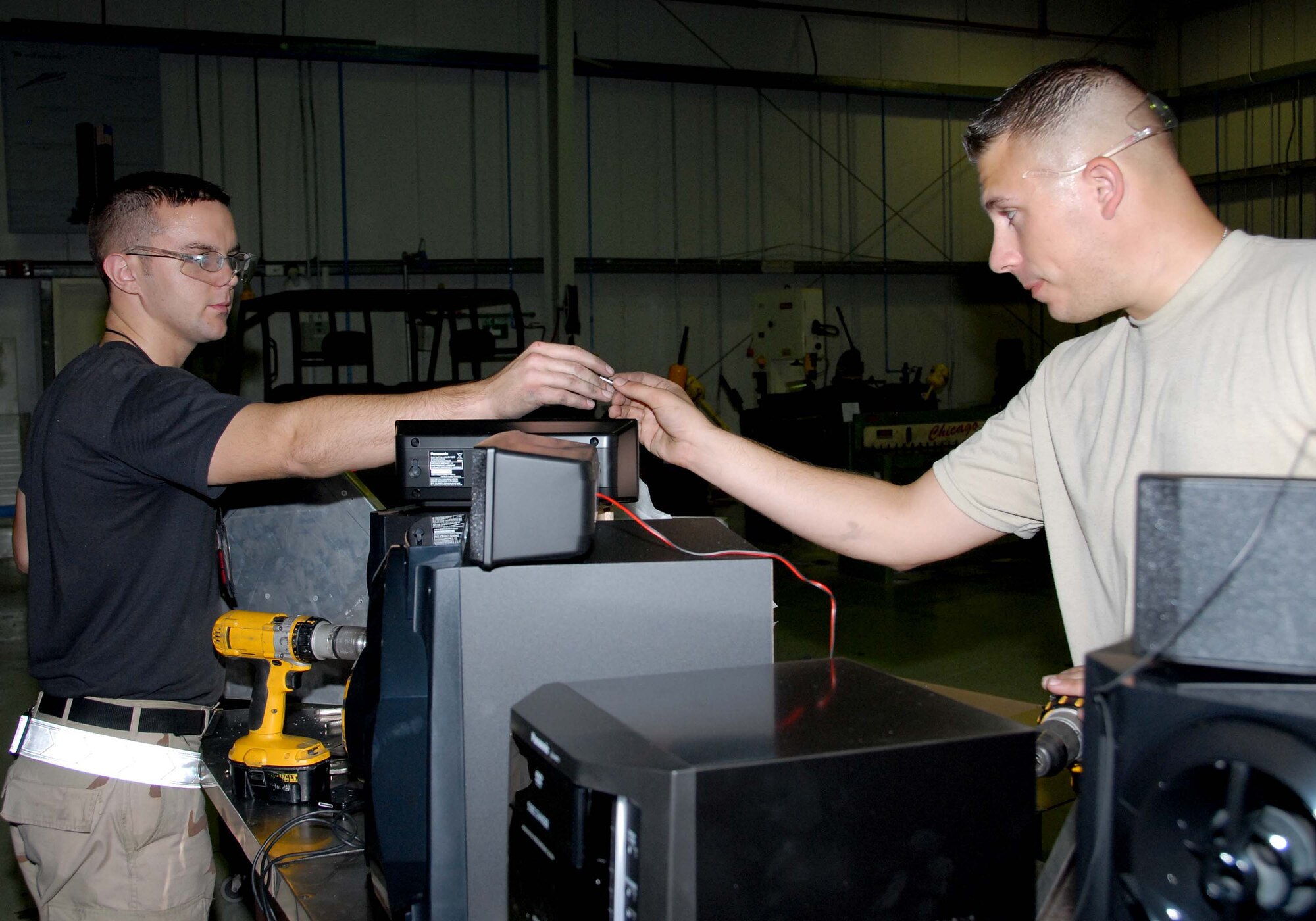 SOUTHWEST ASIA -- Senior Airman Jacob Taylor (left) hands a rivet to Senior Airman Jesse Spears as the two buld shelves in the fabrication shop here Oct. 7. Airmen Taylor and Spears are aircraft structural maintenance journeyman with the 380th Expeditionary Aircraft Maintenance Squadron. Airman Spears is deployed from Tinker Air Force Base, Okla. and calls Mascoutah, Ill., home. Airman Taylor is deployed from Beale AFB, Calif. (U.S. Air Force photo by Tech. Sgt. Denise Johnson) (released)