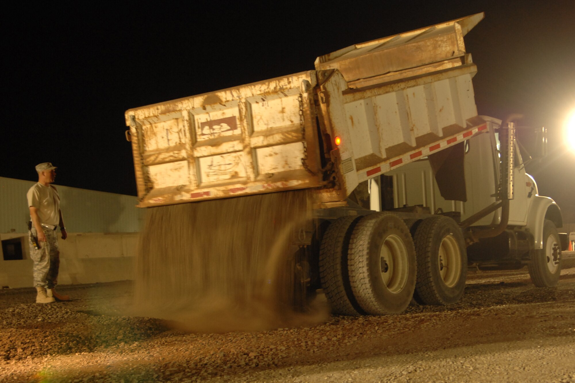 KIRKUK REGIONAL AIR BASE, Iraq -- Senior Master Sgt. Tony Harback, 506th Expeditionary Civil Engineering Squadron heavy equipment superintendent, directs a dump truck during the the dining facility parking lot improvement project here Oct. 12.  The project was conducted to improve the parking lot as well as add organization of parking spaces.  The project included delivering nearly 200 loads of recycled milling asphalt from the runway.  Sergeant Harback is deployed from Luke Air Force Base, Ariz. (U.S Air Force photo/Senior Airman Randi Flaugh)  