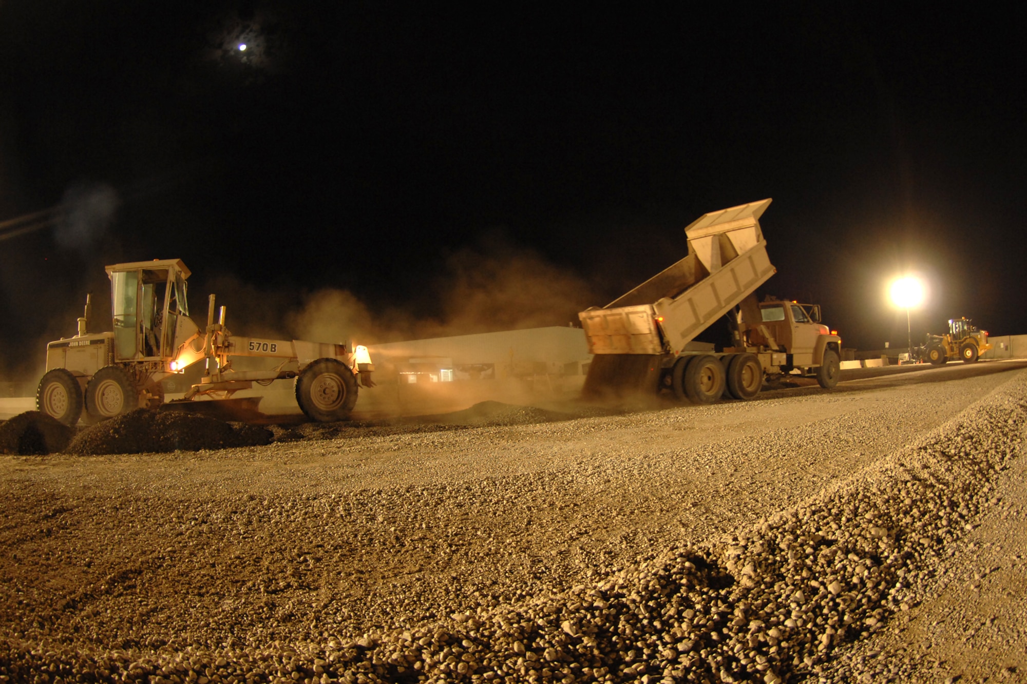 KIRKUK REGIONAL AIR BASE, Iraq -- Airmen from the 506th Expeditionary Civil Engineering Squadron use a front end loader, dump truck and grader during  the dining facility parking lot improvement project here Oct. 12.  The project was conducted to improve the parking lot as well as add organization of parking spaces.  The project included delivering nearly 200 loads of  recycled milling asphalt from the runway. (U.S Air Force photo/Senior Airman Randi Flaugh)  