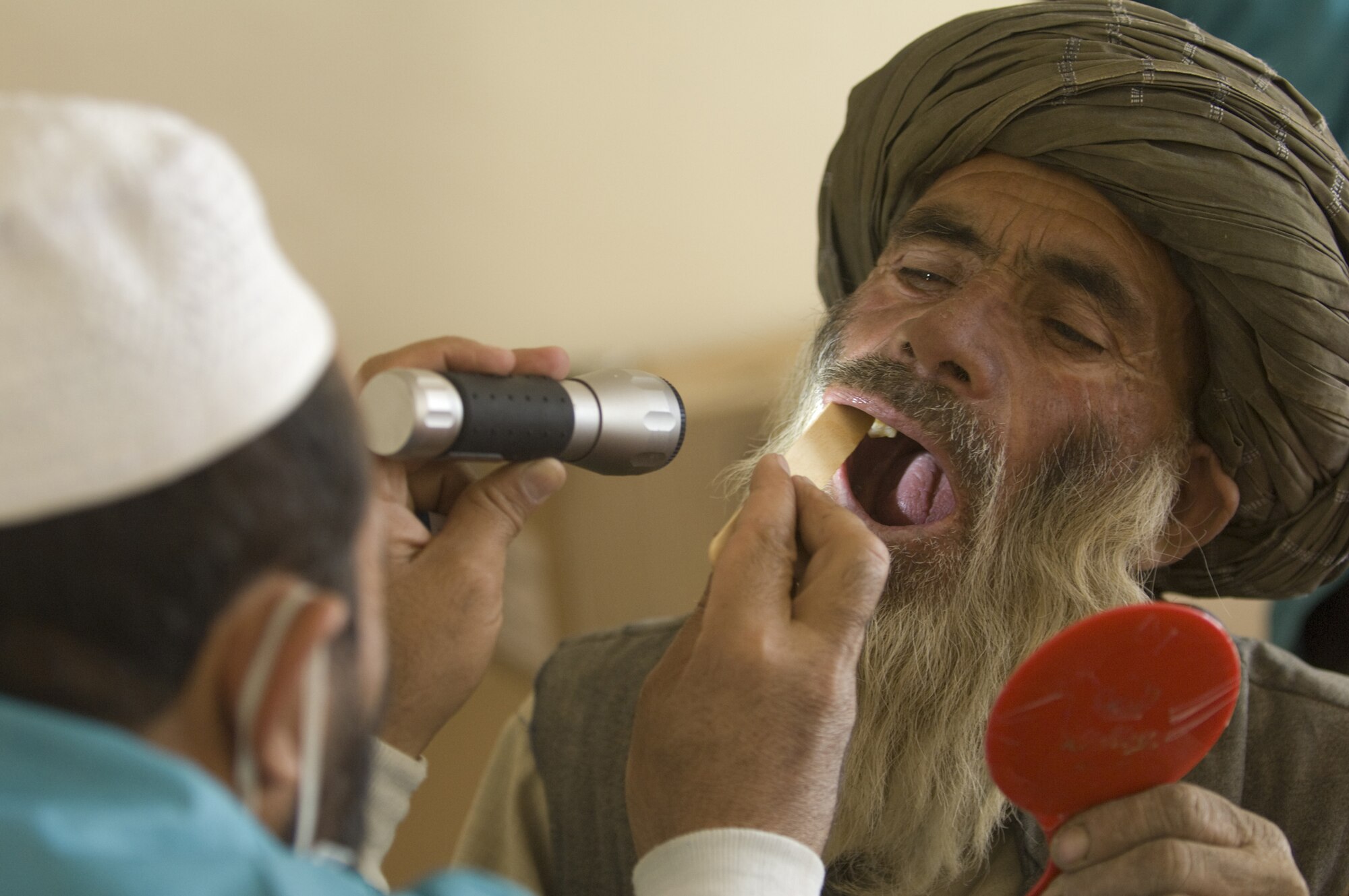 SHAJOY, Afghanistan -- An Afghan dentist, trained by the Zabul Provincial Reconstruction Team, examines an Afghan's teeth and a Village Dental Outreach visit. Although most Afghans lack basic dental hygiene products, their teeth remain relatively healthy due to limited sugar in their diets. When they do have problems many go untreated for years with the lack of basic dental care. The Zabul PRT uses the visits to address these problems, which normally consist of extracting the bad tooth.(U.S. Air Force photo/Master Sgt. Keith Brown)