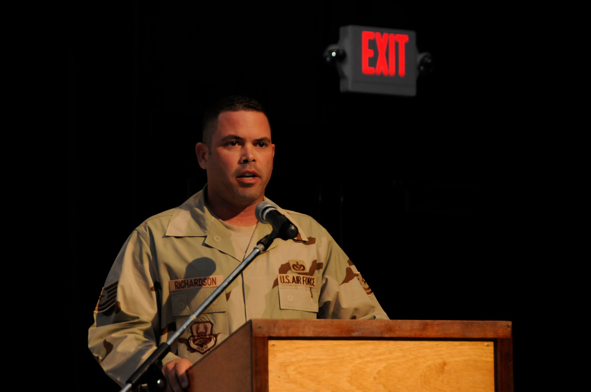 Tech. Sgt. David Richardson, 379th Expeditionary Civil Engineering Squadron, emcees the monthly promotion and recogition ceremony at the Coalition Compound Theater Sept. 30. The Top 4 sponsors the ceremony which recognizes 50 to 80 promotees and award winners per month.  (U.S. Air Force photo by Tech. Sgt. Michael Boquette)