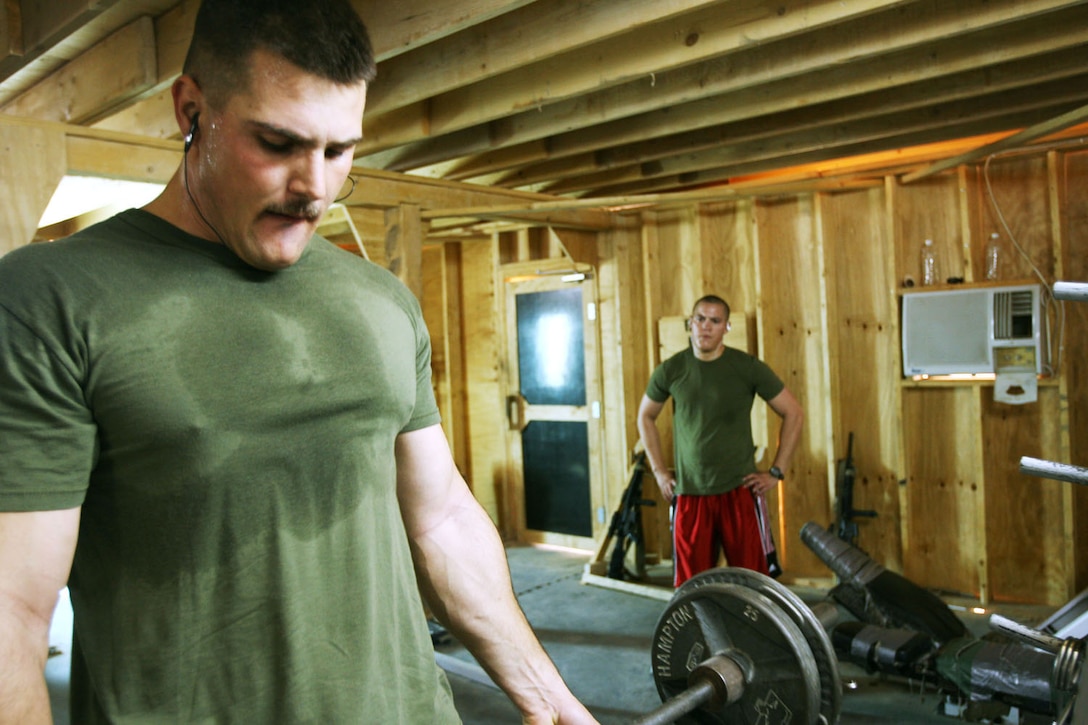Cpl. Chad R. Hochstatter, 23, studies the technique of Cpl. Arron M. Stephens, 27, a former personal trainer, as he lifts weights in the weight room at Camp Hit, Iraq, Oct. 19.  Both Marines are administrative clerks for Headquarters and Service Compnay, 3rd Battalion, 7th Marine Regiment, Regimental Combat Team 5.  Stephens has been a certified personal trainer with the International Sport and Science Association for six years and has been helping Marines in the battalion get into shape while deployed to Iraq.::r::::n::