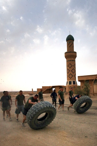 Marines with Task Force 3rd Battalion, 7th Marine Regiment, Regimental Combat Team 5 flip a truck tire around the perimeter of Camp Hit, Iraq, during a CrossFit competition Oct. 24.  The Marines competed against each other in a number of different exercises such as pull-ups and dumbbell cleans.  The competition was thought up to raise morale and help the Marines gauge how fit they've become over the past few months.::r::::n::