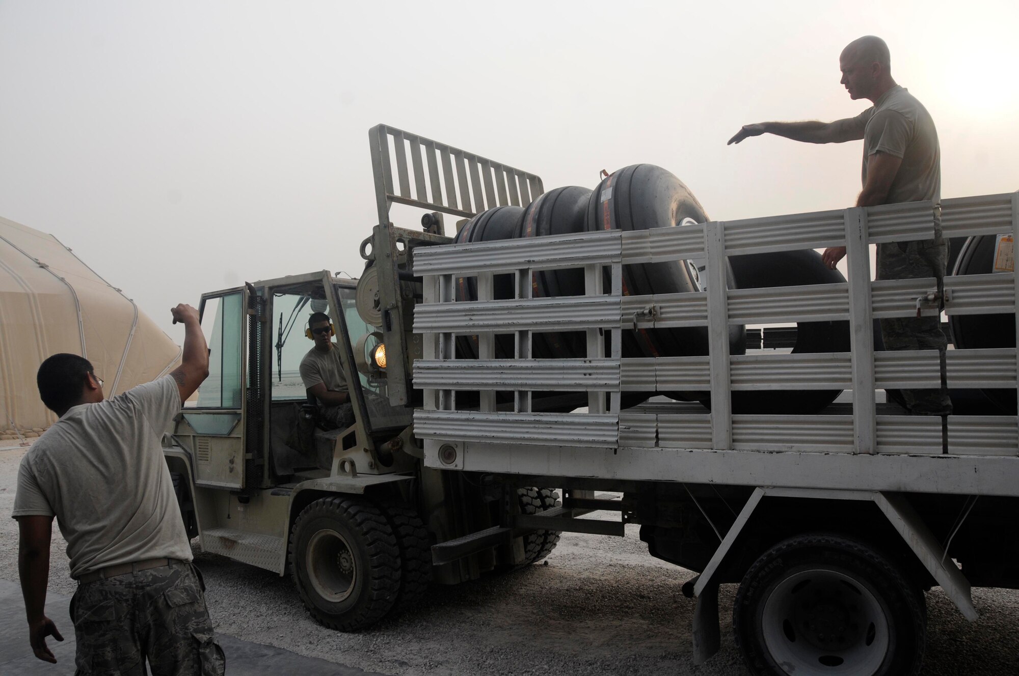 Senior Airman Moises Maramba, a supply specialist assigned to the 379th Expeditionary Logistics Readiness Squadron, guides a forklift driven by Senior Airman David Drake, also a supply specialist assigned to the 379 ELRS, to a truck bed where Staff Sgt. Daryl Reid, warehouse supervisor assigned to the 379 ELRS, awaits to unload the tires Oct. 18, 2008, at an undisclosed air base in Southwest Asia. All three Airmen work in the Centralized Intermediate Repair Facility where they are responsible for expediting shipments of aircraft tires throughout the entire Air Forces Central area of responsibility. Airman Maramba, a native of Bronx, N.Y., is deployed from MacDill Air Force Base, Fla.  Airman Drake, a native of Long Beach, Calif., and Sergeant Reid, a native of Phoenix, Ariz., are both deployed from Mountain Home Air Force Base, Idaho.  All three are deployed in support of Operations Iraqi and Enduring Freedom and Joint Task Force-Horn of Africa. (U.S. Air Force photo by Staff Sgt. Darnell T. Cannady/Released)