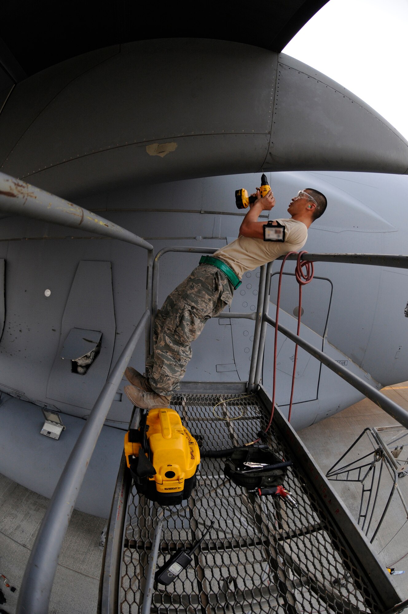 Airman 1st Class Matthew Enter, 379th Expeditionary Maintenance Squadron, uses all the leverage he can get to drill out a stripped screw head, October 17, 2008, at an undisclosed air base in Southwest Asia.  The bad screws are being removed so the crew chiefs can pull the panel and do maintenance on a C-17 Globemaster III.  Airman Enter, a native of Rochester, N.Y., is deployed from Fairchild Air Force Base, Wash., in support of Operations Iraqi and Enduring Freedom and Joint Task Force-Horn of Africa.  (U.S. Air Force photo by Tech. Sgt. Michael Boquette/Released)