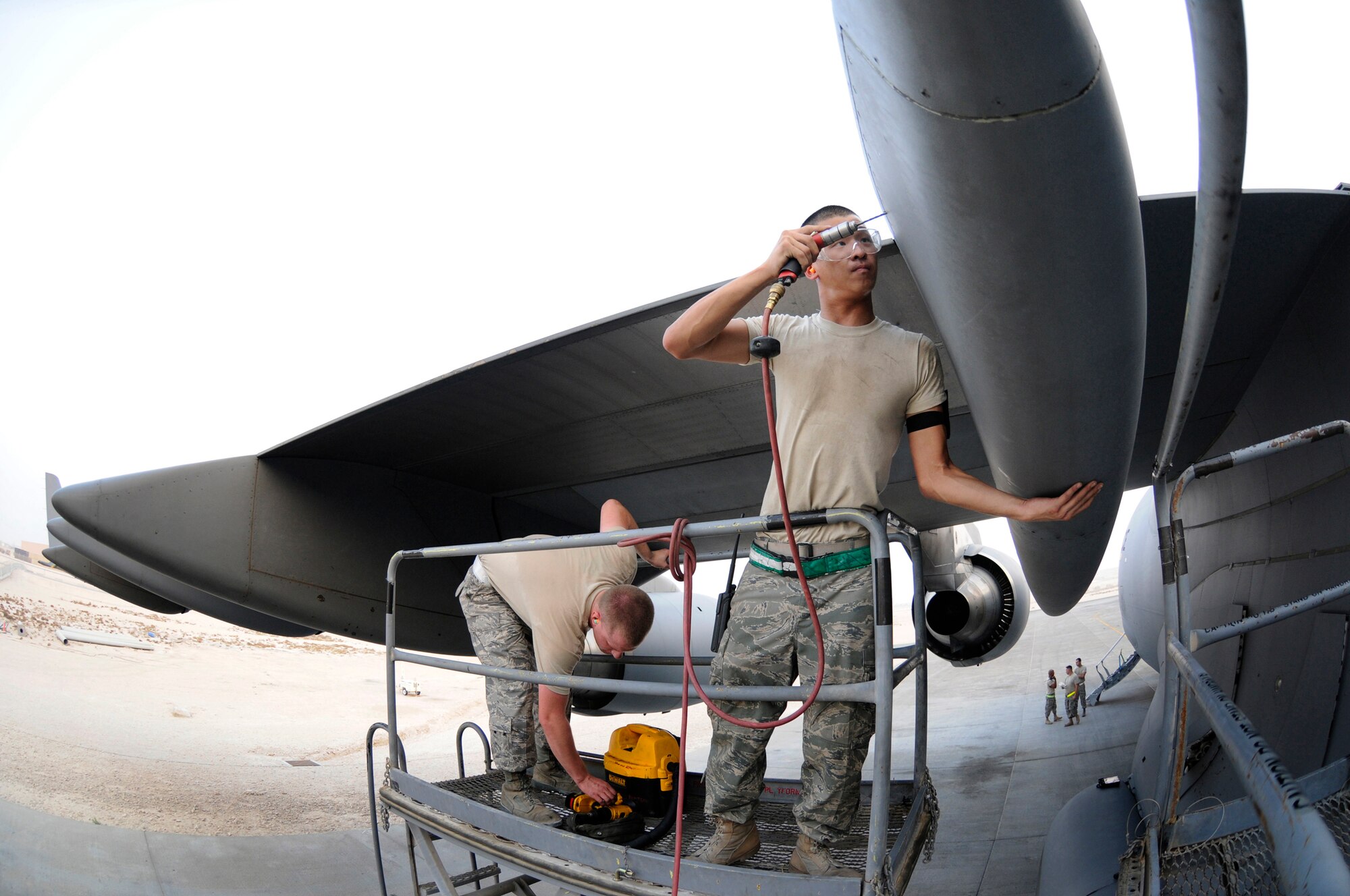 Airman 1st Class Matthew Enter, 379th Expeditionary Maintenance Squadron, uses a power drill to remove a stripped screw head, October 17, 2008.  Senior Airman Mark McMichael, EMXS, reaches for a vacuum to capture any fragments that come apart during drilling.  The bad screws are being removed so crew chiefs can pull the panel and do maintenance on a C-17 Globemaster III at an undisclosed air base in Southwest Asia.  Airman McMichael, a native of Denver, Colo., is deployed from Charleston Air Force Base, S.C., and Airman Enter, a native of Rochester, N.Y., is deployed from Fairchild AFB, Wash. Both Airmen are deployed in support of Operations Iraqi and Enduring Freedom and Joint Task Force-Horn of Africa.  (U.S. Air Force photo by Tech. Sgt. Michael Boquette/Released)