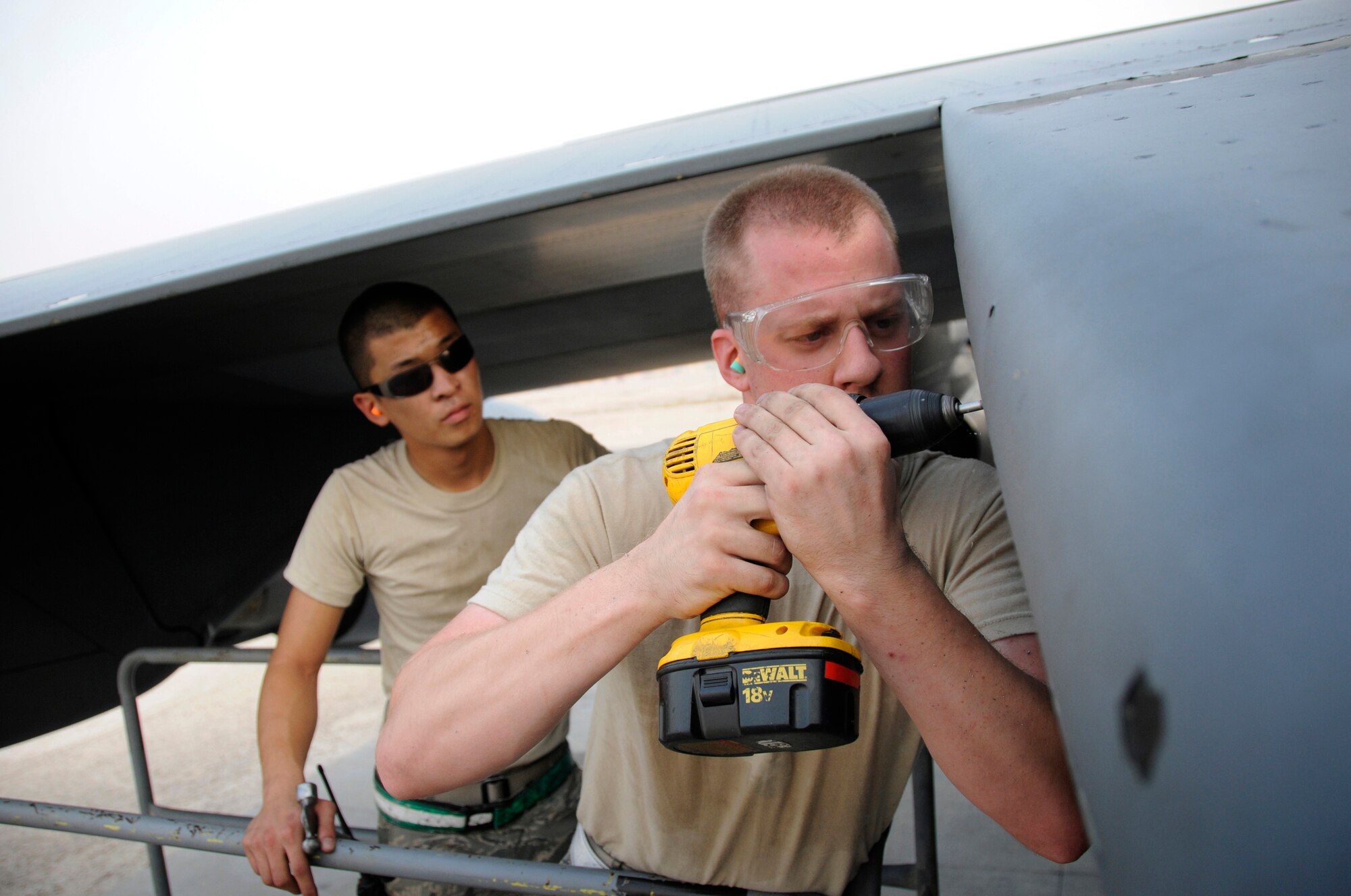 Senior Airman Mark McMichael gives total concentration to drilling out a stripped screw head while Airman 1st Class Matthew Enter stands ready to tap it out if necessary, October 17, 2008, at an undisclosed air base in Southwest Asia.  Both Airmen are deployed to the 379th Expeditionary Maintenance Squadron in support of Operations Iraqi and Enduring Freedom and Joint Task Force-Horn of Africa.  The bad screws are being removed so the crew chiefs can pull the panel and do maintenance on a C-17 Globemaster III.  Airman McMichael, a native of Denver, Colo., is deployed from Charleston Air Force Base, S.C., and Airman Enter, a native of Rochester, N.Y., is deployed from Fairchild AFB, Wash.  (U.S. Air Force photo by Tech. Sgt. Michael Boquette/Released)