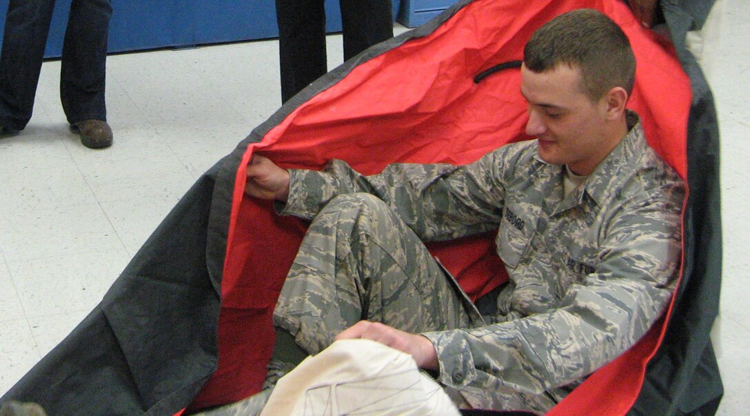 Airman Basic Billy DeBord, a student in the 361st Training Squadron, demonstrates how to inspect a one-man life raft for members of the Wichita Falls Junior League during a tour Oct. 16. The civic group explored the equipment sewing, survival raft, and parachute packing training programs at the 361st TRS along with a windshield and visit to the Heritage Center. (U.S. Air Force photo/Debi Smith)