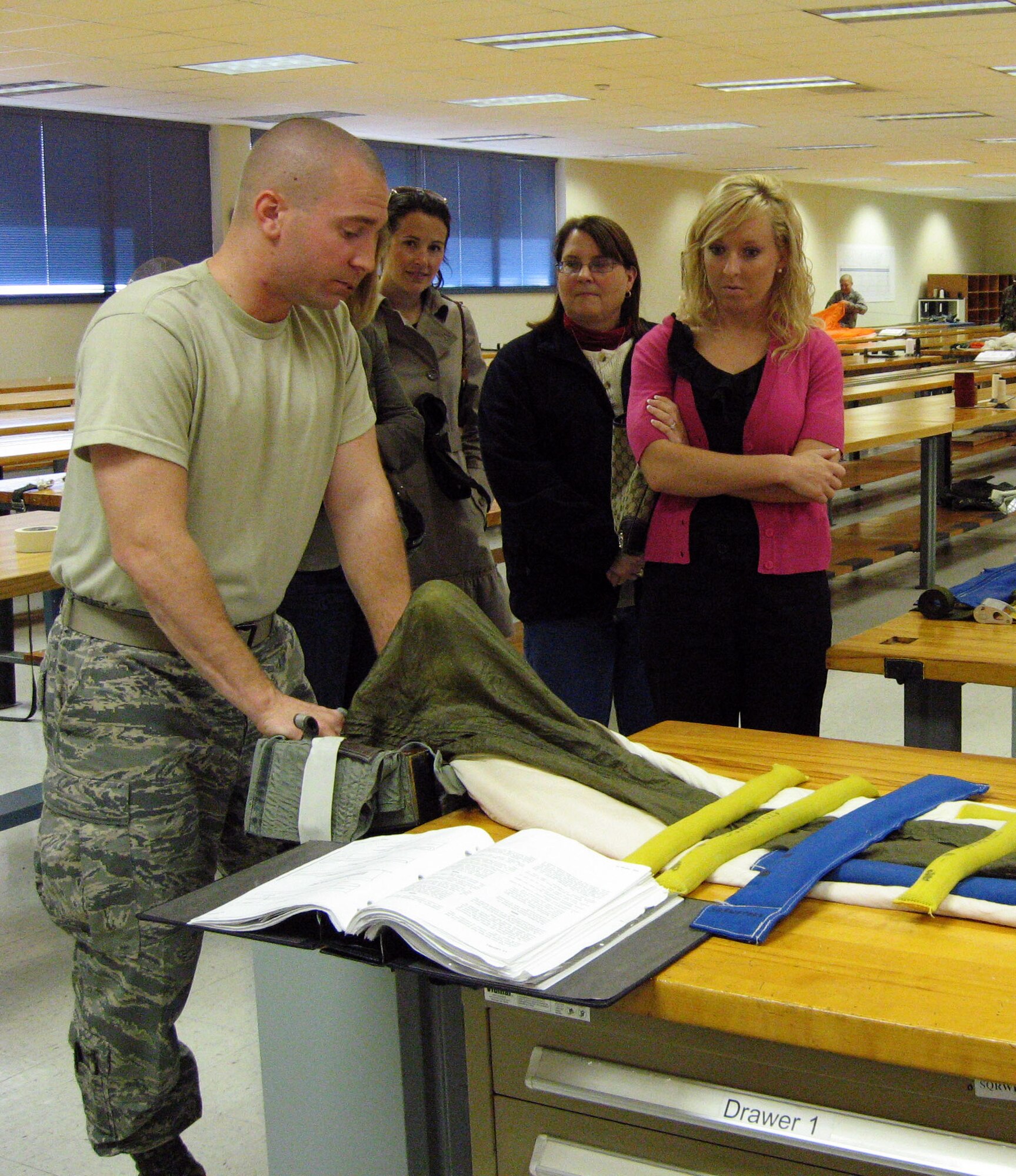 Airman Basic Brian Grieder, a student in the 361st Training Squadron, demonstrates how to pack a Advanced Concept Ejection Seat parachute for members of the Wichita Falls Junior League during a tour Oct. 16. The civic group explored the equipment sewing, survival raft, and parachute packing training programs at the 361st TRS along with a windshield and visit to the Heritage Center. (U.S. Air Force photo/Debi Smith)