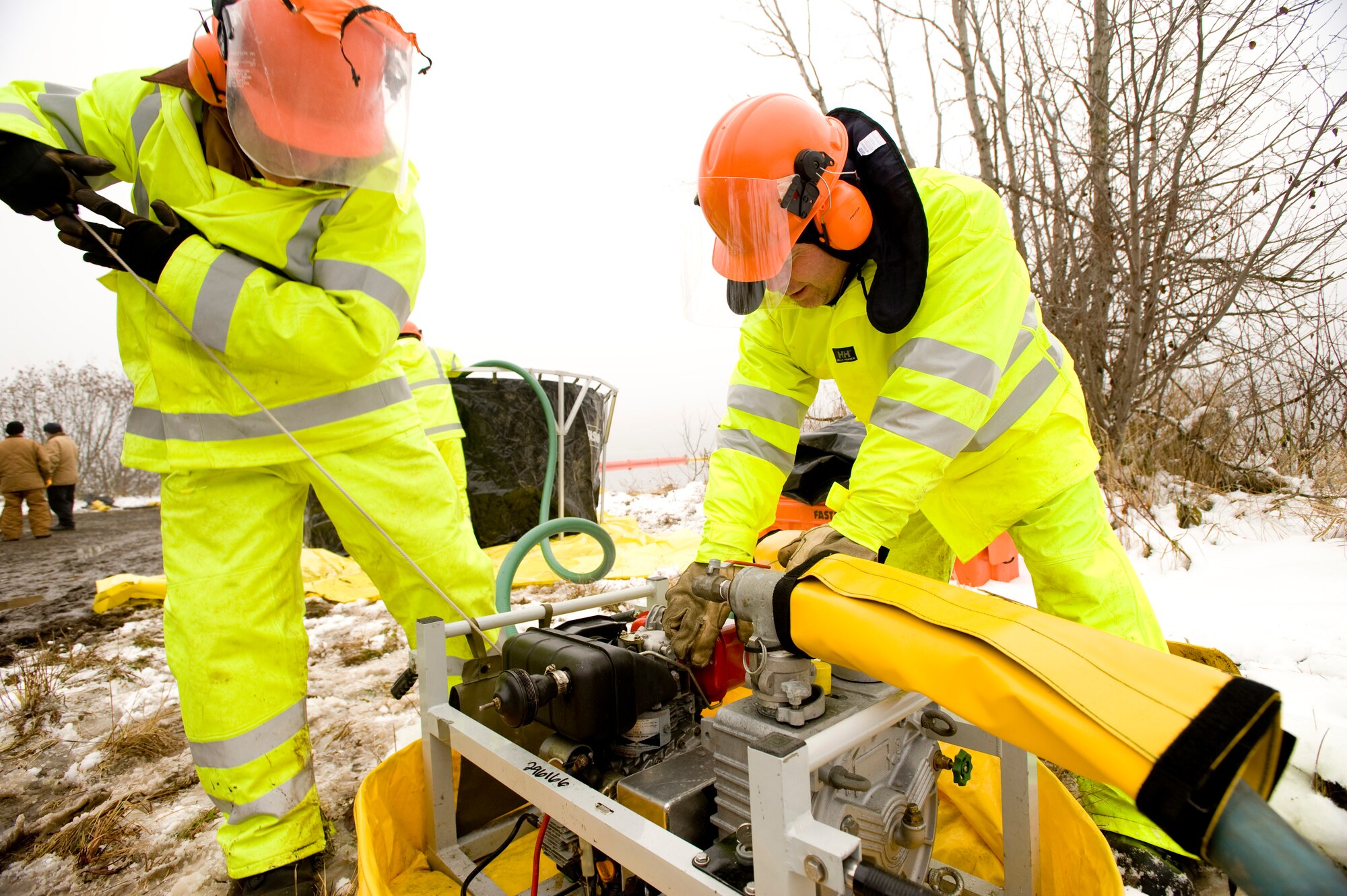 ELMENDORF AIR FORCE BASE, Alaska -- Senior Airman Benjamin Tackett and Steve Brunk, 611th Civil Engineer Squadron, starts up a water pump used to move the oil from tank to tank at Sixmile Lake Oct. 16. With an oil spill, multiple water pumps and tanks are used to filter the water and oil from each other. (U.S. Air Force photo/Senior Airman Jonathan Steffen)