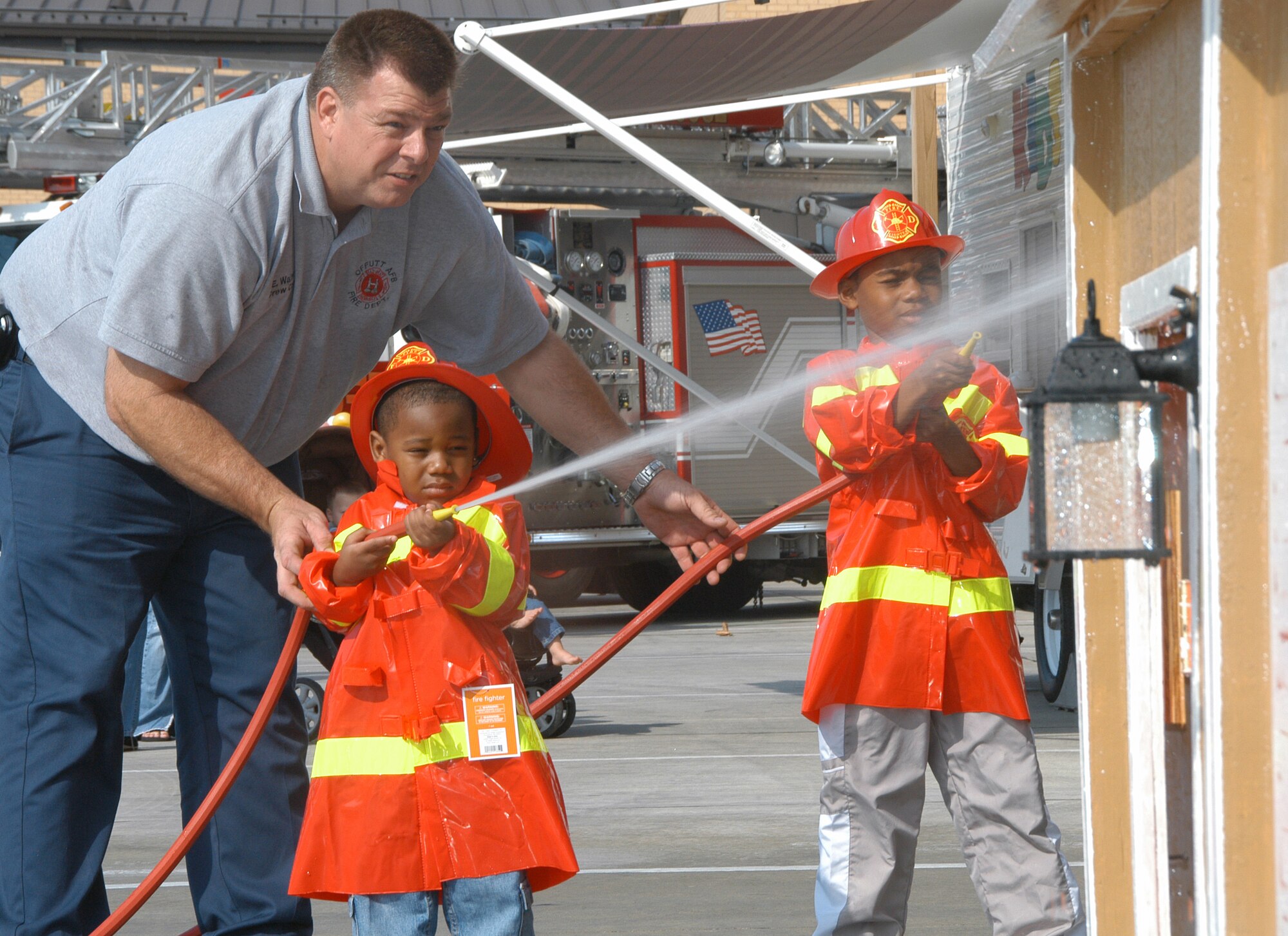 OFFUTT AIR FORCE BASE, Neb. -- Fire Captain Ed Walter gives instructions to A.J. Little, age two, and D.J. Fisher, age six, sons of Staff Sgt. Shavonda Fisher, U.S. Strategic Command, on how to handle a fire hose and where to spray water during the 2008 Offutt Fire Station Open House Oct. 11. (U.S. Air Force Photo By Jeff Gates)                                                                                                                                                                       