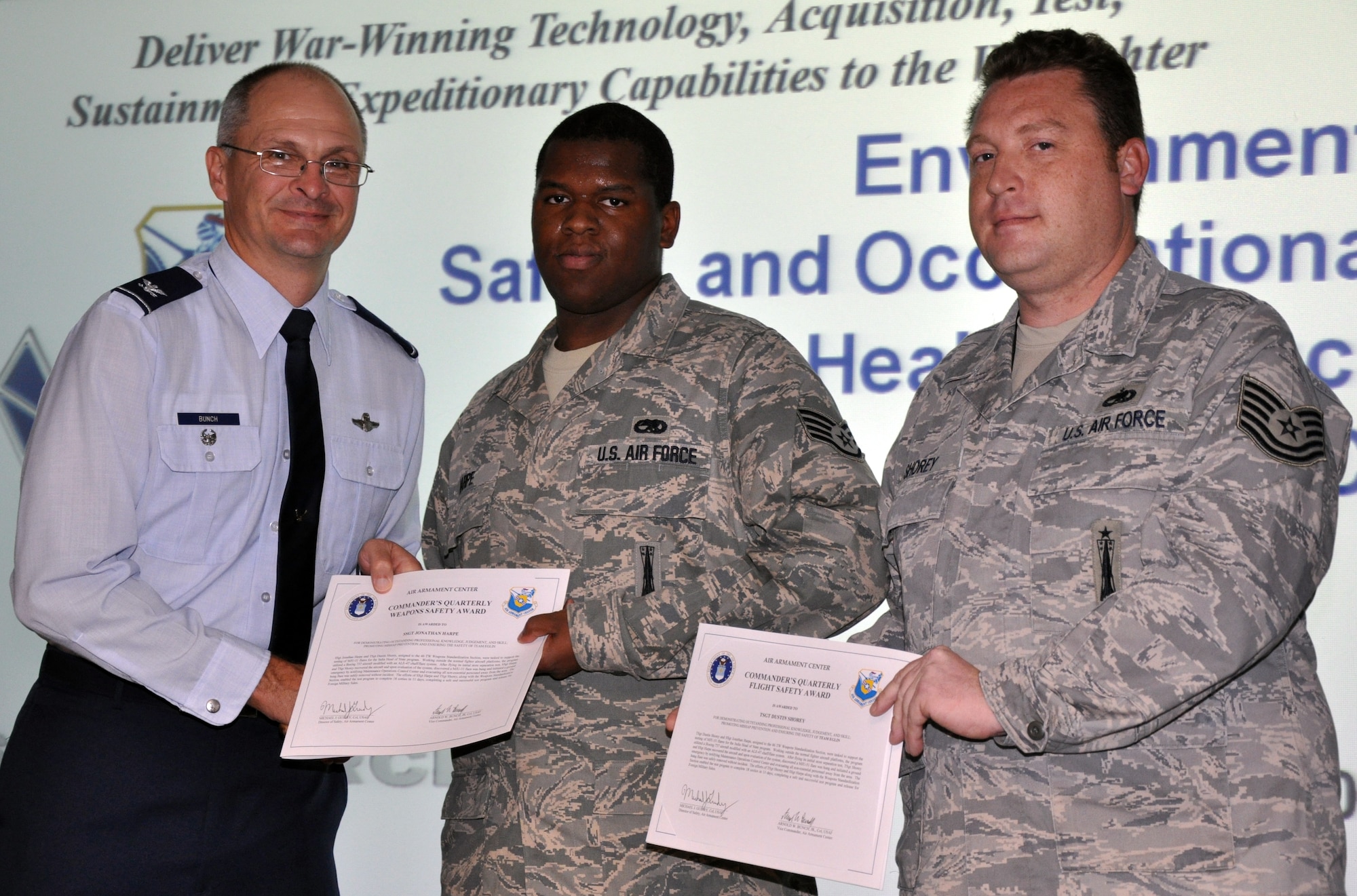 EGLIN AIR FORCE BASE, Fla. -- Col. Arnold Bunch, Air Armament Center vice commander, presents Tech. Sgt. Dustin Shorey, 46 Aircraft Maintenance Squadron, and Staff Sgt. Jonathan Harpe, 46 Aircraft Mainenance Group, with the Commander's Quarterly Flight Safety Award for his outstanding professional knowledge, judgement and skill promoting mishap prevention and ensuring the safety of Team Eglin. (US Air Force photo/ Airman 1st Class Anthony Jennings)