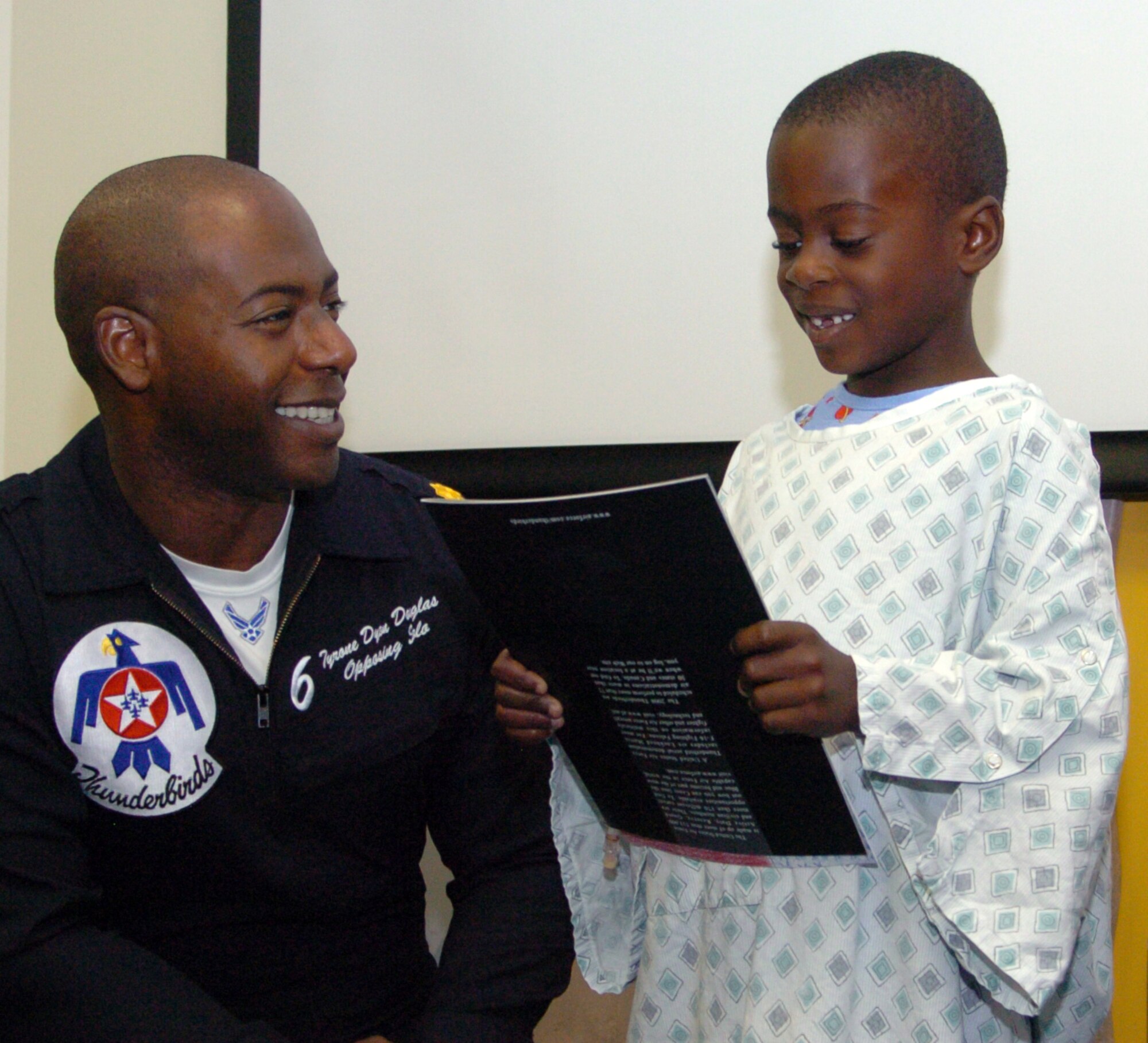 Jordan Headley, age 5, is all smiles after receiving a 2008 Thunderbirds Program from Maj. Tyrone Douglas, U.S. Air Force Thunderbirds No. 6 F-16 pilot, at the Children's Healthcare of Atlanta Pediatric Hospital. "We enjoy the opportunity to have a one-on-one visit with children," said Maj. Charla Quayle, USAF Thunderbirds flight surgeon. "It inspires and empowers them to follow their dreams." The Thunderbirds also visited two metro Atlanta area high schools as part of their community relations visits in connection with their appearance at the Wings over Marietta Air Show and Open House at Dobbins Air Reserve Base, Oct. 18-19. (U.S. Air Force photo/Master Sgt. Stan Coleman)