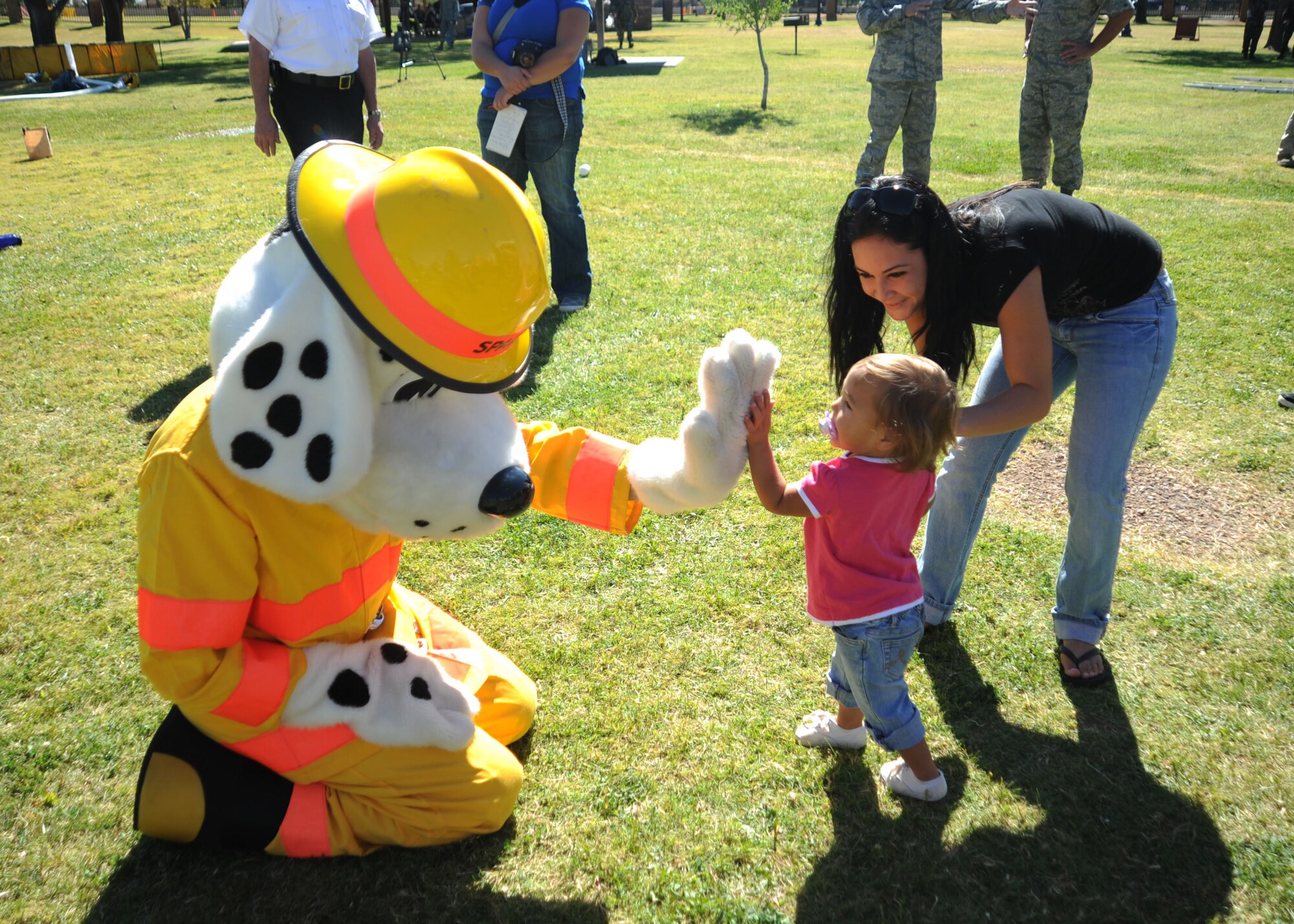 CANNON AIR FORCE BASE N.M.-- Jomarie Lopez and daughter Kailanyz Rodriguez high-five Sparky the Fire Department Mascot Oct 10. Sparky helped cheer on the contestants as they dashed through Fire Prevention Week's Fire Muster's various events. (U.S. Air Force photo by Airman Maynelinne De La Cruz) 