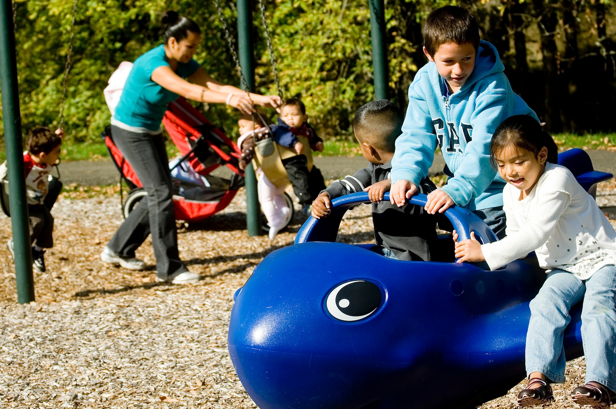 From right, Iris Noguez, Adrian Rodriguez and Mauricio Noguez have fun on playground equipment at a McChord park while Catalina Noguez swings the younger children. (U.S. Air Force photo/Abner Guzman)