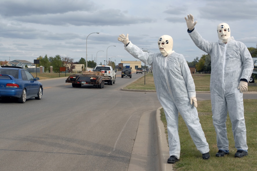 MINOT AIR FORCE BASE, N.D. – Tech. Sgt. Erica Robinson, 5th Bomb Wing, and her husband, Staff Sgt. Jonathan Robinson, 5th Logistics Readiness Squadron, wave to vehicles leaving the base while dressed in crash test dummy costumes to promote safe driving here Oct. 10.  The Robinson’s, both active in the Airmen Against Drunk Driving program, were also reminding base personnel to call AADD if their original plan fell through. (U.S. Air Force photo by Senior Airman Kelly Timney)