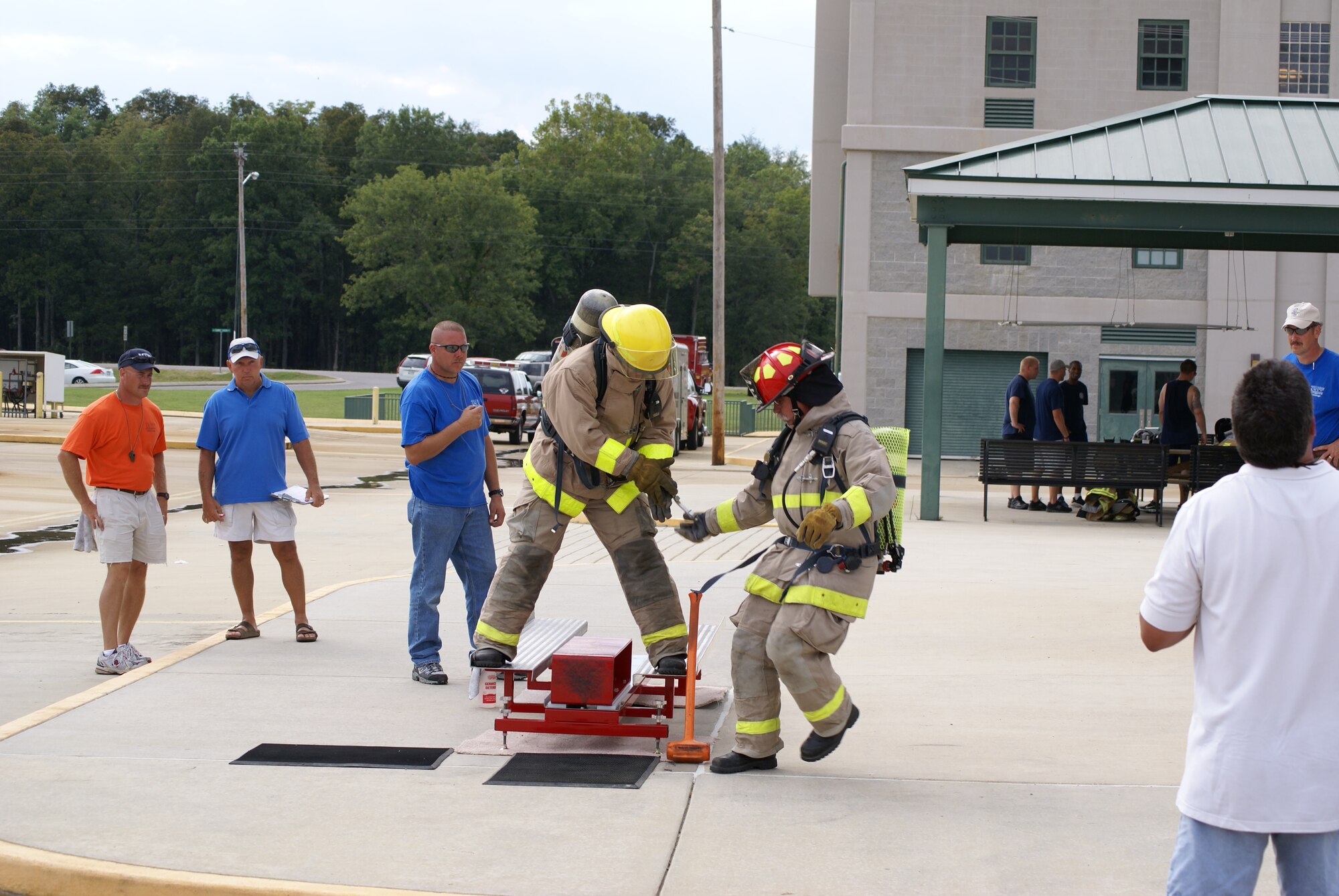Jay Baldwin passes the baton to Charlie Armstrong during an exercise which simulates what is physically required to forcibly enter a secure building. This requires the fireman to use an eight-pound sledge hammer to strike a metal weight back five feet. (Photo by Wade Campbell)