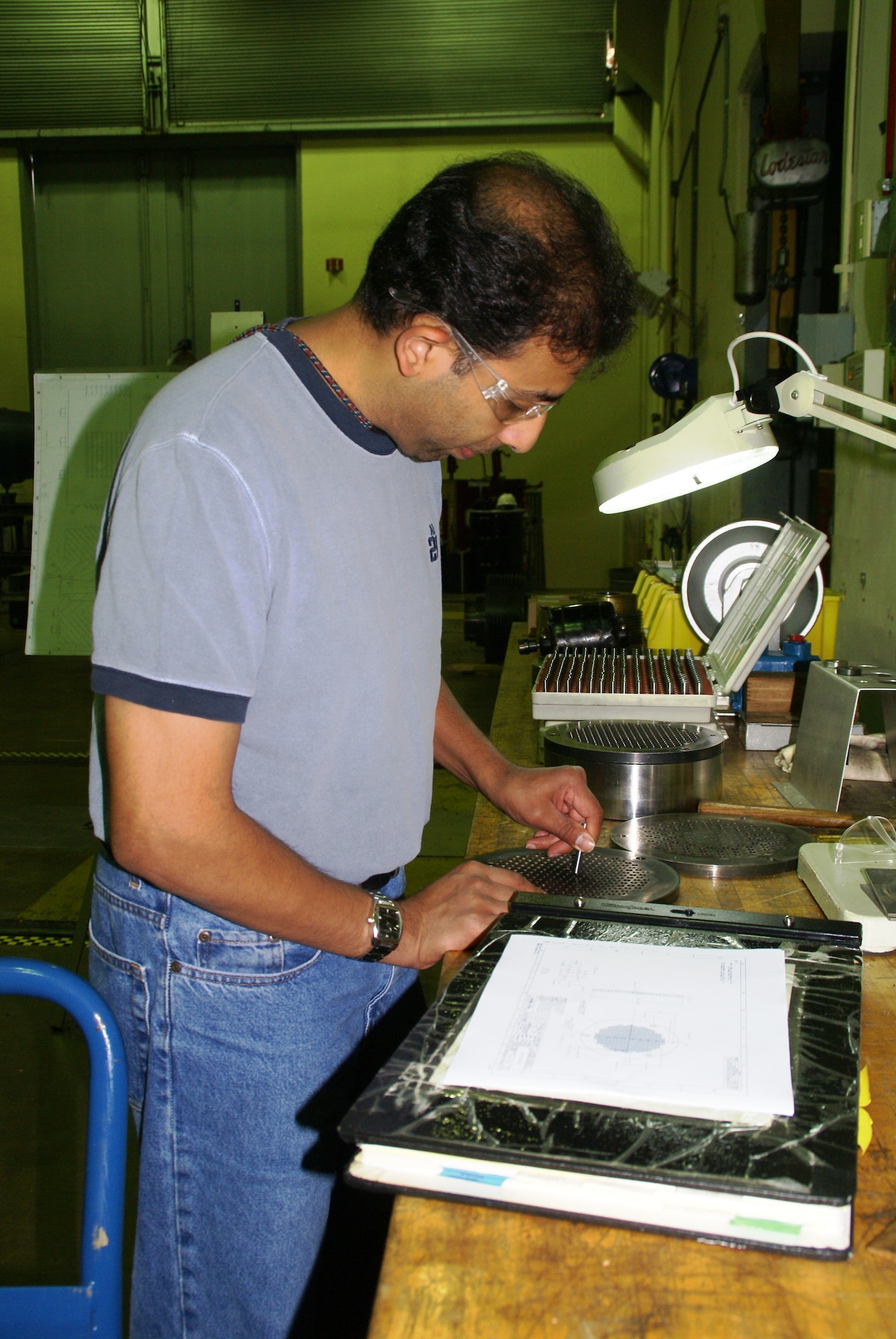 Madhav Rao, an Aerospace Testing Alliance (ATA) systems engineer at AEDC’s Hypervelocity Wind Tunnel 9, inspects one of the holes for ablators that fit into a flow restrictor assembly, which controls flow conditions in the test cell. Ablators, in this case, are materials that lose material from their surface by vaporization and friction during reentry into the Earth’s atmosphere. Rao is measuring the holes as part of a redesign effort on the ablator retaining plate, which holds them in place when subjected to simulated reentry conditions during a test. ATA is the support contractor for Arnold. (Photo by Philip Lorenz III)