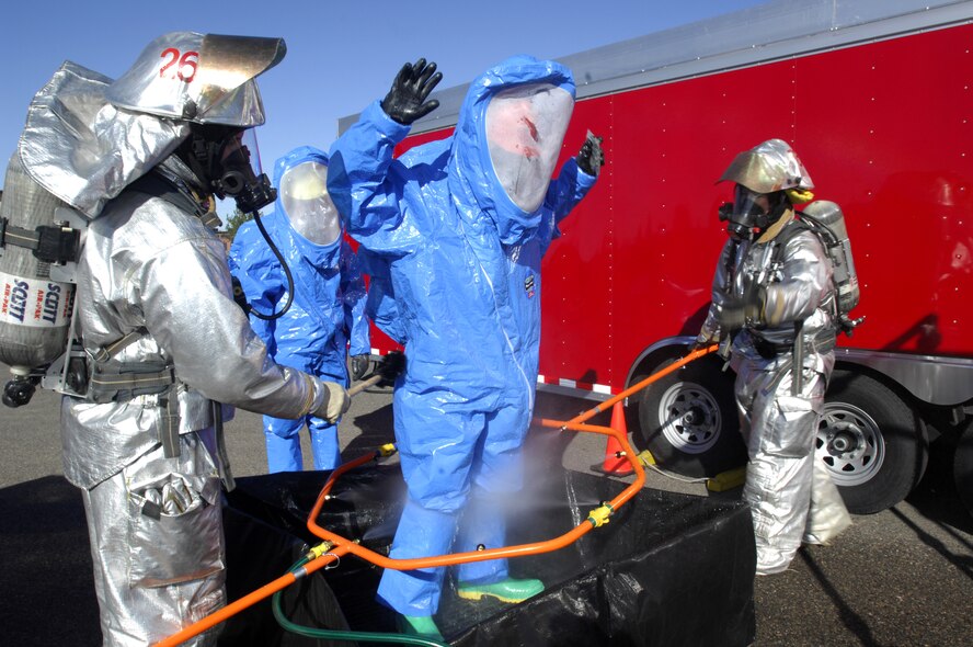 MINOT AIR FORCE BASE, N.D. -- Airman 1st Class Derrick Wager, 5th Civil Engineer Squadron firefighter, is decontaminated by Senior Airman Daniel Payne and Staff Sgt. Darnell Dobson, both 5th CES firefighters, following a simulated chemical attack on the gym during the All-Hazards Response Training exercise here Oct. 15. The exercise was designed to test responding agencies’ capabilities during a crisis scenario. (U.S. Air Force photo by Airman 1st Class Jesse Lopez)