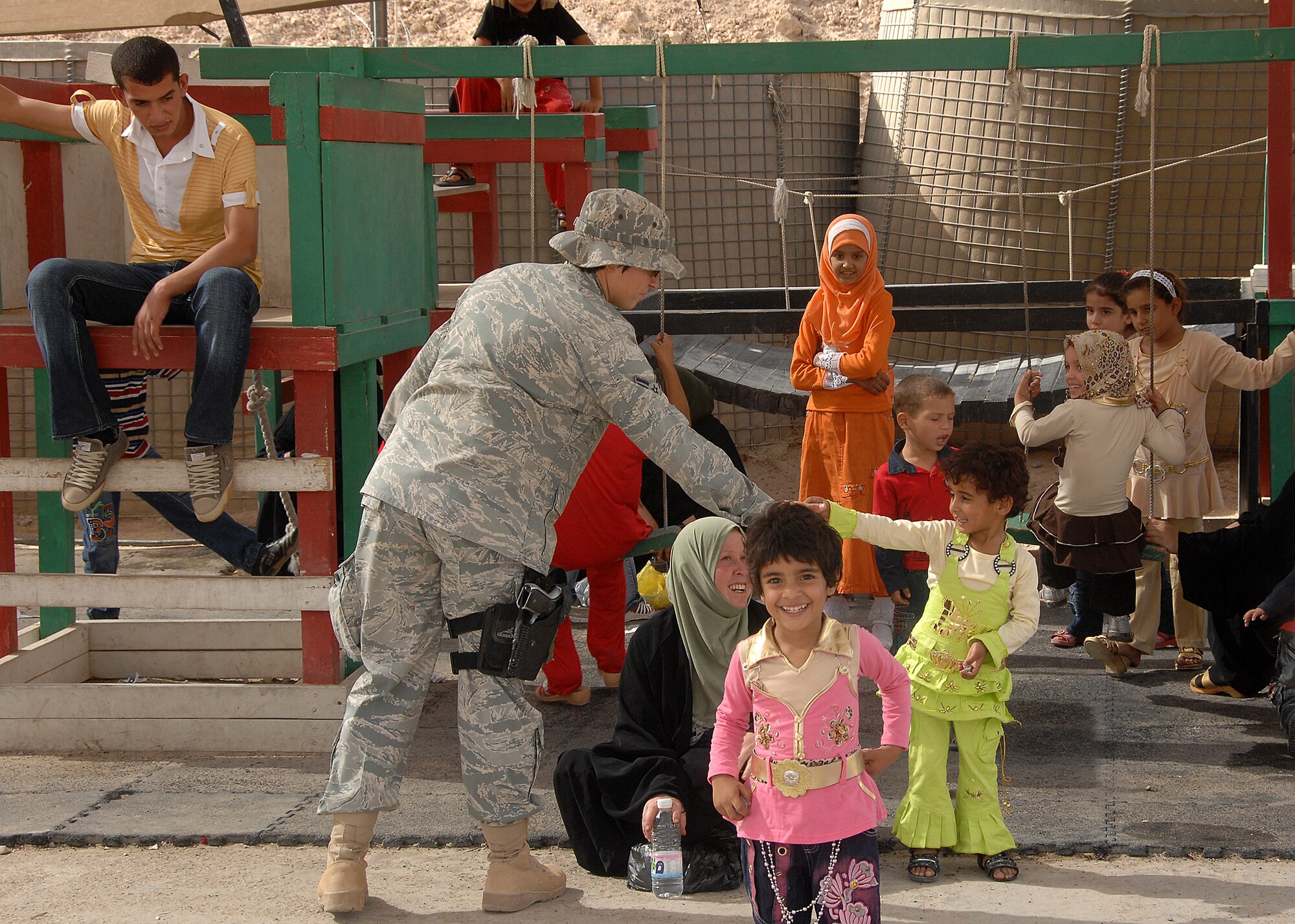 Southwest Asia -- A security forces member from the 586th Air Expeditionary Group plays with Iraqi children on Sept. 29 at Camp Bucca, Iraq,  while they wait for transport to the detainee visitation center. The 586th AEG provides security and transport to the center for nearly 400 visitors who are allowed to visit daily with detainees being held at the Theater Internment Facility. 