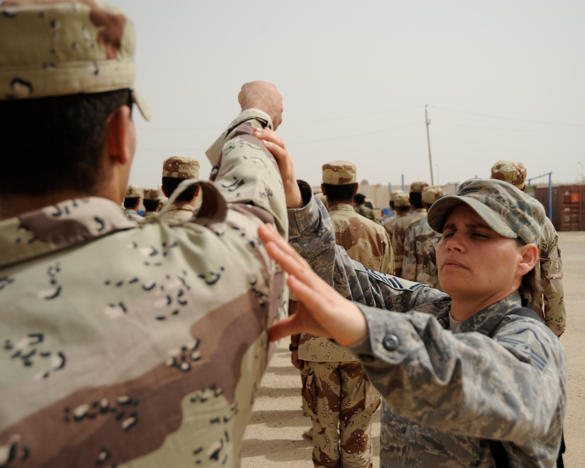 AL TAJI AIR BASE, Iraq -- U.S. Air Force Master Sgt. Jennifer Rabidoux, basic military training superintendent, 370th Expeditionary Training Squadron, corrects an Iraqi warrant officer's arm swing during parade practice.. Rabidoux, a Bayonne, N.J. native, advises the Iraqi MTI's on how to conduct drill, physical training, dorm set up and lectures. (U.S. Air Force photo/Staff Sgt. Paul Villanueva II)