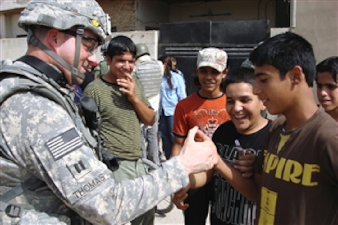 U.S. Army Capt. Christopher Thomas takes time out to play a friendly game of thumb wrestling with an Iraqi boy during a patrol in the New Baghdad Security District of eastern Baghdad, Iraq, Oct. 14, 2008. Thomas is commander of the 66th Armored Regiment's Company A, 1st Battalion.