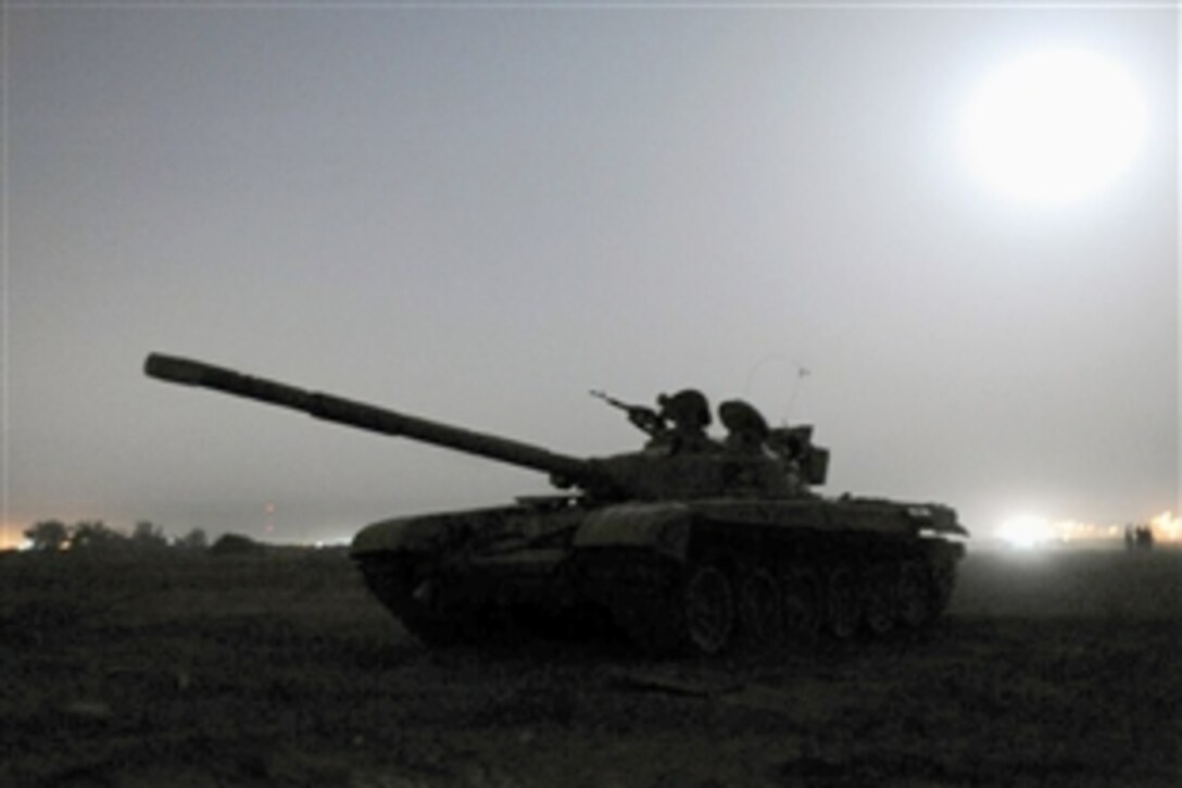 U.S. Army soldiers supervise while an Iraqi Army T-72 tank pulls security during an early morning training exercise on Camp Taji, Iraq, Oct. 14, 2008. The U.S. soldiers are assigned to the 25th Infantry Division.