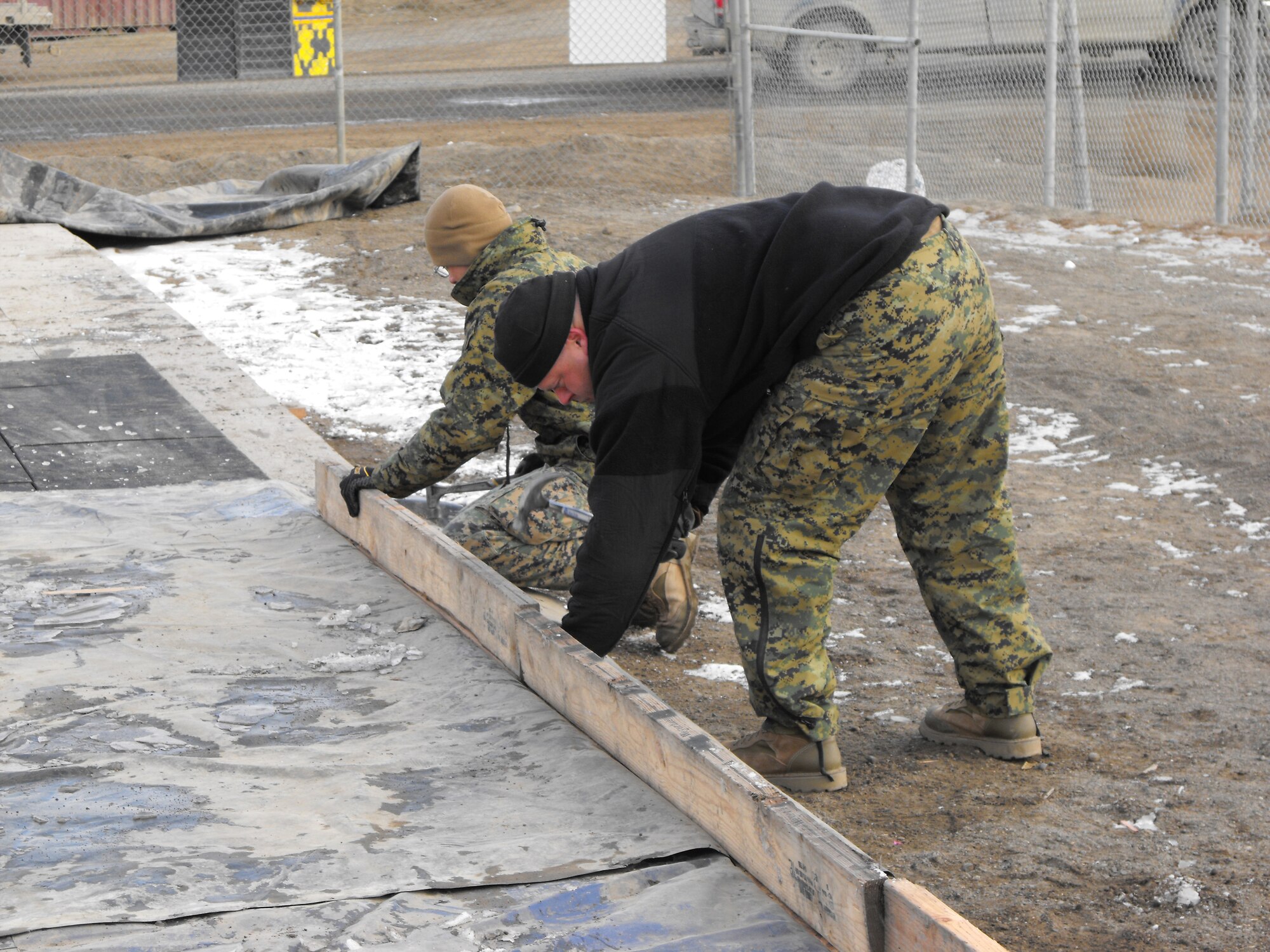 BARROW, Alaska -- Navy Chief Petty Officer Jay Olson and Marine Corp Gunnery Sgt. Bradley Miller assemble the border of future ice rink. The Company built the rink on the community basketball court for ice skating during the winter months. (Courtesy photo)