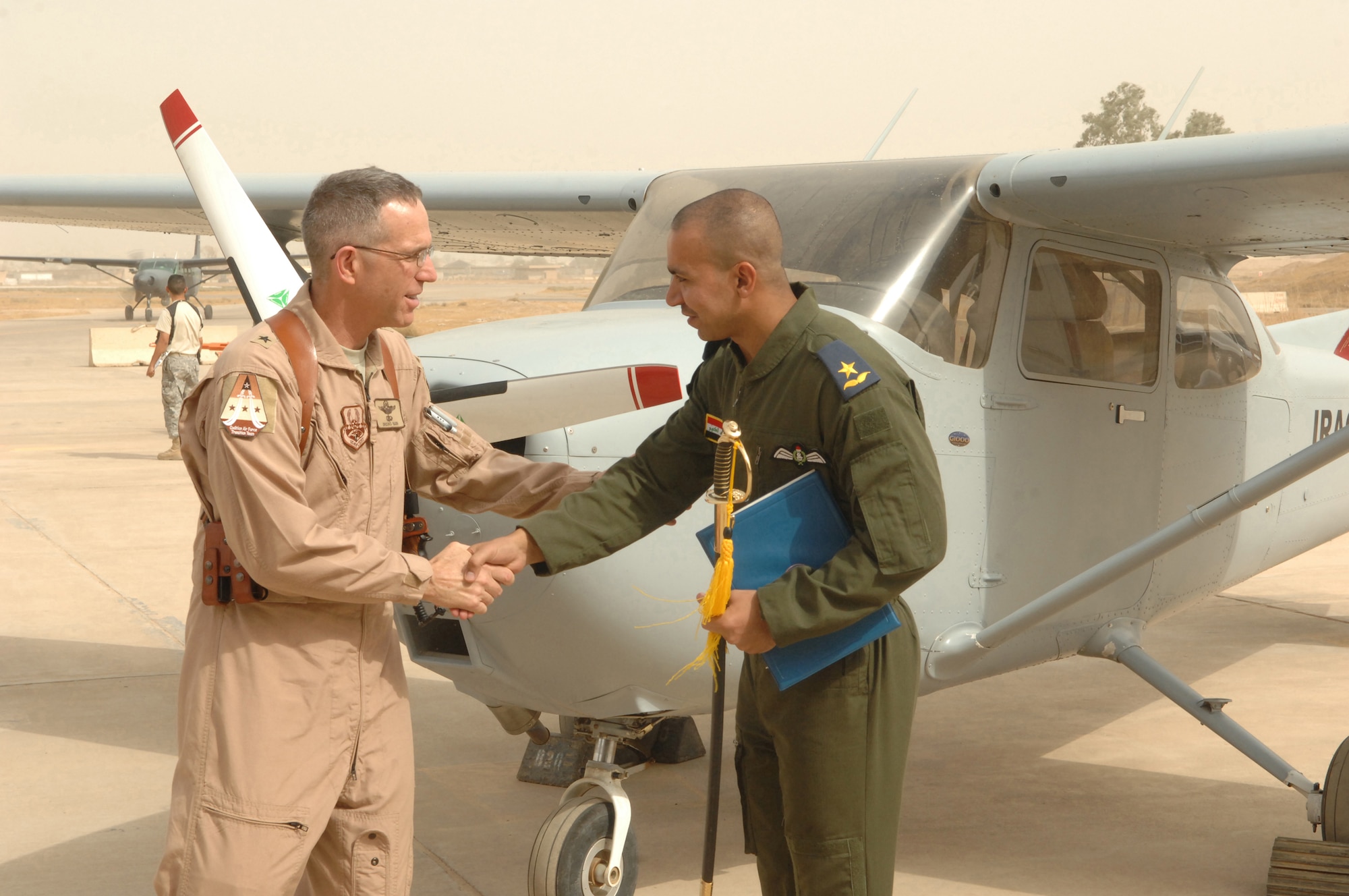 Brig. Gen. Brooks Bash gives a congratulatory handshake to Iraqi air force 2nd Lt. Hassan at Kirkuk Regional Air Base, Iraq, Oct.13. Lieutenant Hassan and two other Iraqi airmen were the first class to graduate from Iraq?s only fixed-wing flight training school. General Bash is the Coalition Air Force Transition Team commander. (U.S. Air Force photo/Senior Airman Randi Flaugh)