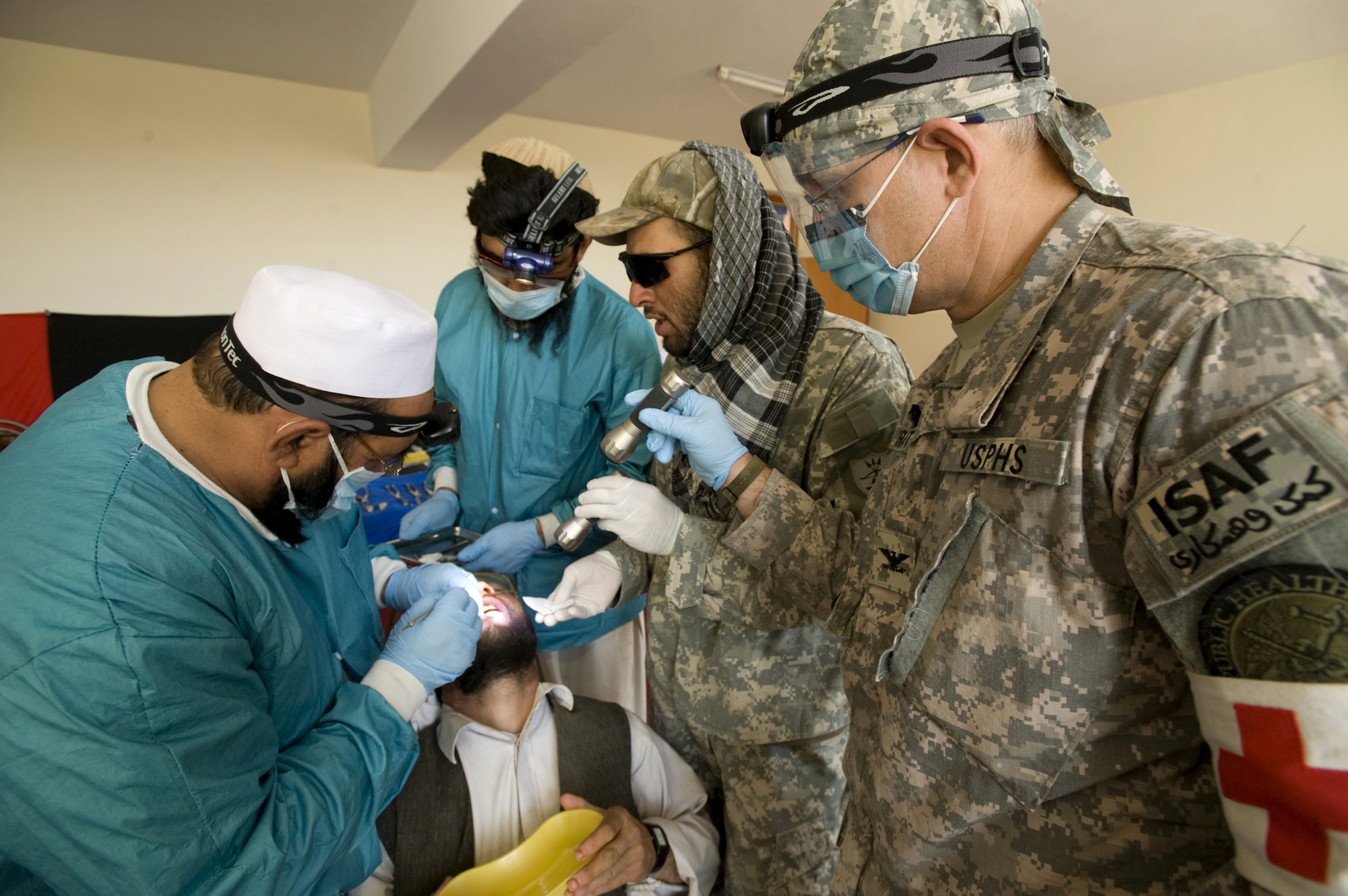 Capt. (Dr.) Charles Craft watches as Afghan dentists examines an Afghan's teeth during a village dental outreach visit Oct. 11 in Zabul, Afghanistan. Captain Craft provided the dentist and Zabul Provincial Reconstruction Team medics five-weeks of field dental care training. The course was launched here to enhance the skills of four area non-governmental organization dental professionals; providing them the ability to establish free field clinics with infection control standards in place to offer emergency extractions and routine cleanings. Captain Craft is with the U.S. Public Health Service. (U.S. Air Force photo/Master Sgt. Keith Brown) 
