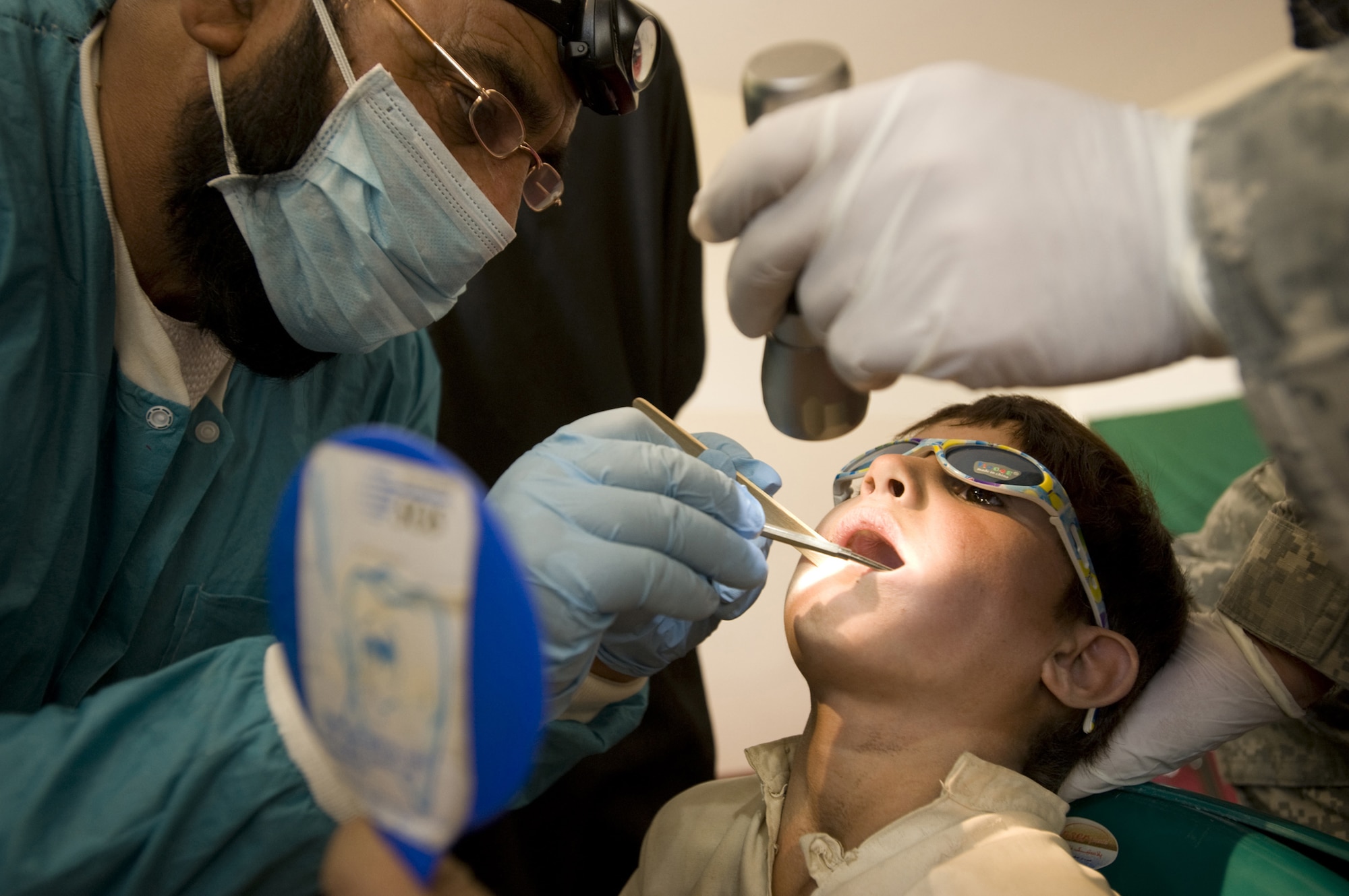 Noorullah Agha, trained by members of the Zabul Provincial Reconstruction Team, examines an Afghan's teeth during a village dental outreach visit Oct. 11 in Zabul, Afghanistan. Although most Afghans lack basic dental hygiene products, their teeth remain relatively healthy due to limited sugar in their diets. When they do have problems many go untreated for years with the lack of basic dental care. (U.S. Air Force photo/Master Sgt. Keith Brown) 
