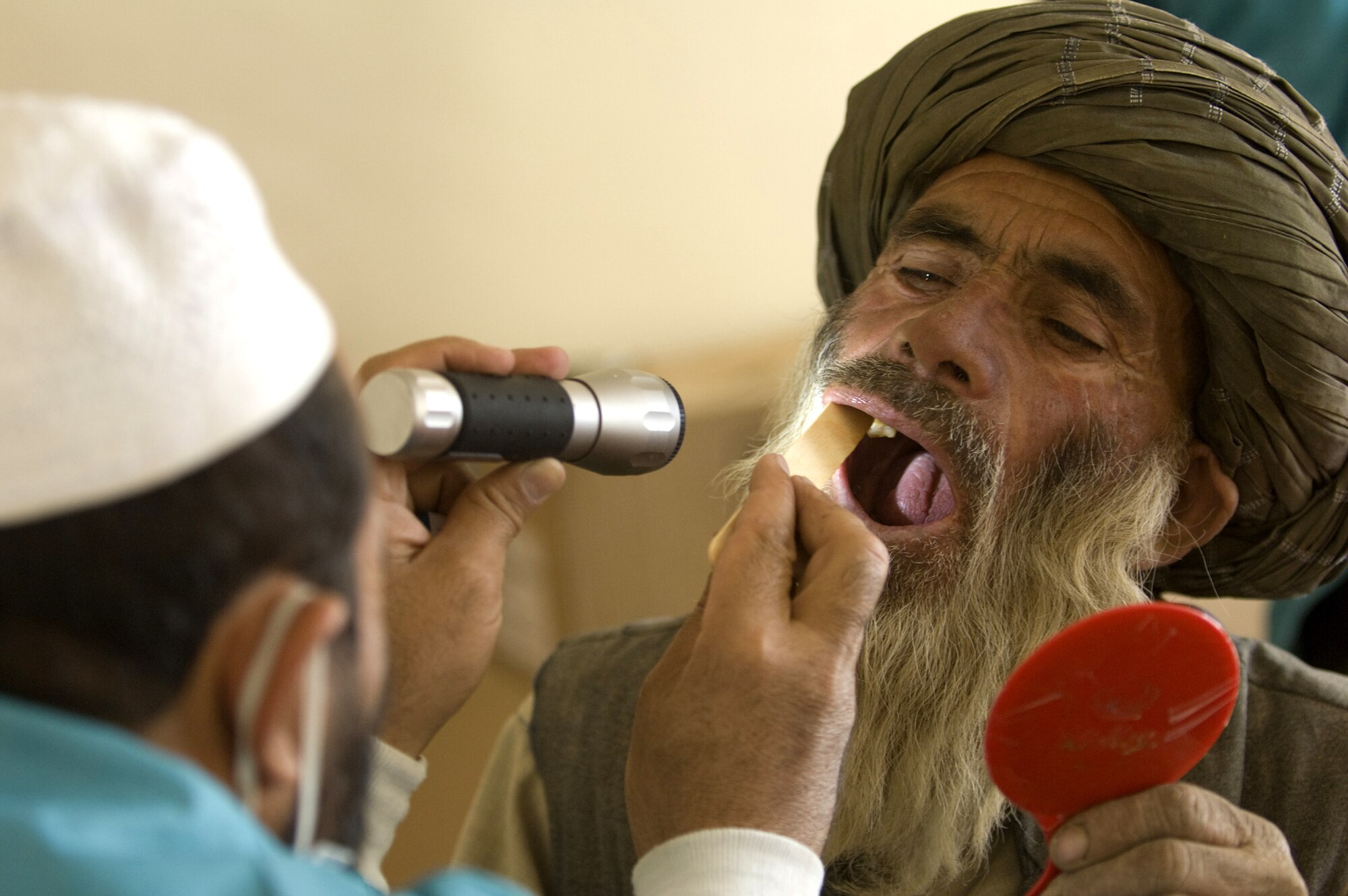 An Afghan dentist, trained by members of the Zabul Provincial Reconstruction Team, examines an Afghan's teeth during a village dental outreach visit Oct. 11 in Zabul, Afghanistan. Although most Afghans lack basic dental hygiene products, their teeth remain relatively healthy due to limited sugar in their diets. When they do have problems, many go untreated for years with the lack of basic dental care. The Zabul PRT used the visits to address these problems, which normally consist of extracting bad teeth.(U.S. Air Force photo/Master Sgt. Keith Brown) 
