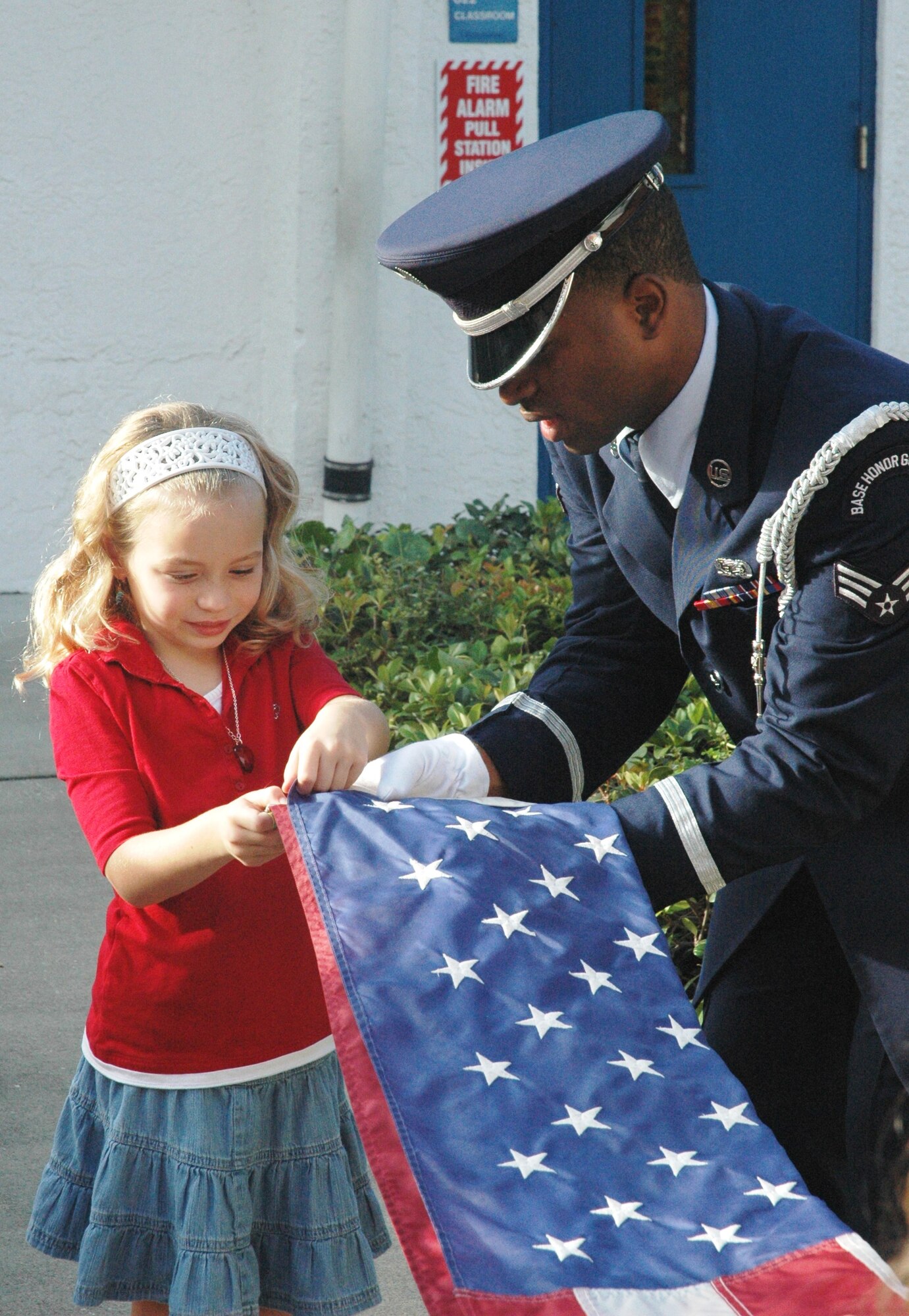 Allie Shelton, a Lynn Haven Elementary third grader, is instructed on proper flag folding etiquette by Senior Airman Darnell Jones, a Tyndall Air Force Base Honor Guard member.  The Honor Guard spent Tuesday morning educating Mrs. Amy Harvey’s class on proper raising and lowering of the flag, a responsibility the class recently were assigned.  (U.S. Air Force photo by:  Capt. Amanda Ferrell)  