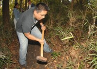 Edgar Olivares, of the Fourth Communications Squadron, tackles a stump with a sledge hammer to clear a path for the haunted trail behind Kimpo Park here on Seymour Johnson Air Force Base. The haunted trail will run from Tuesday October 28 to Halloween Night from 1900 to 2200. (U.S. Air Force Photo by Airman 1st Class Rae A. Perry)