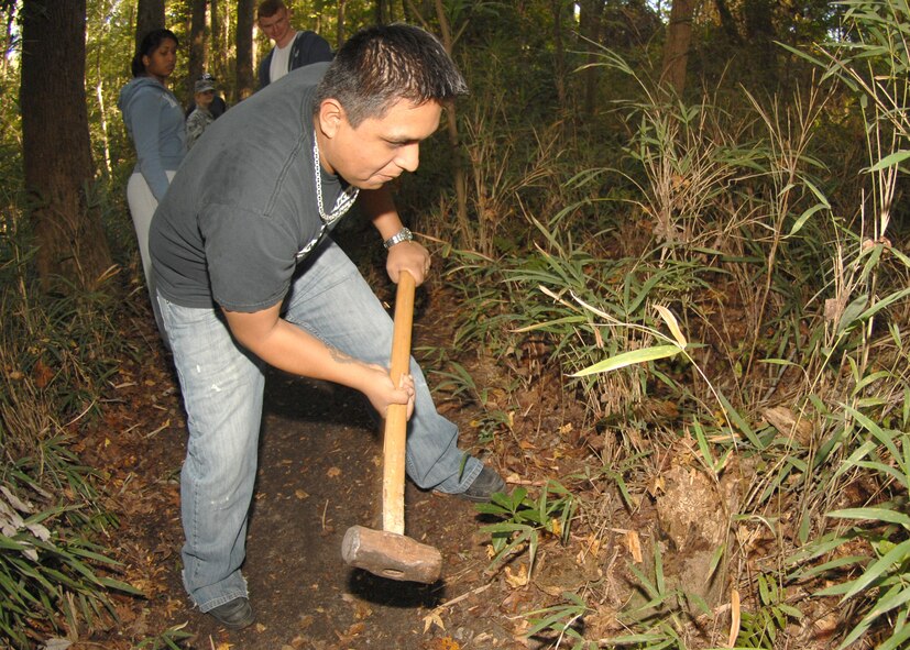 Edgar Olivares, of the Fourth Communications Squadron, tackles a stump with a sledge hammer to clear a path for the haunted trail behind Kimpo Park here on Seymour Johnson Air Force Base. The haunted trail will run from Tuesday October 28 to Halloween Night from 1900 to 2200. (U.S. Air Force Photo by Airman 1st Class Rae A. Perry)