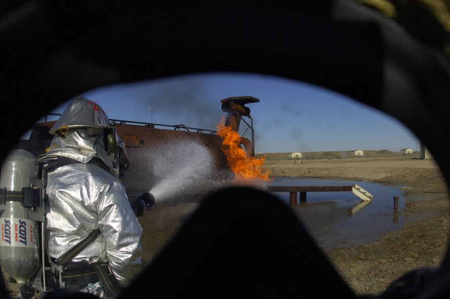 MINOT AIR FORCE BASE, N.D. – As seen from the view of a firefighter, Senior Airman Phillip Haffner, 5th Civil Engineer Squadron firefighter, pushes in toward the flames of a burning plane simulator during an aircraft-fire training scenario here Oct. 20. The scenario was part of a joint training exercise where firefighters from both the city of Minot, N.D., and Minot AFB participated in several scenarios to enhance mission effectiveness. (US Air Force photo by Senior Airman Cassandra Jones)