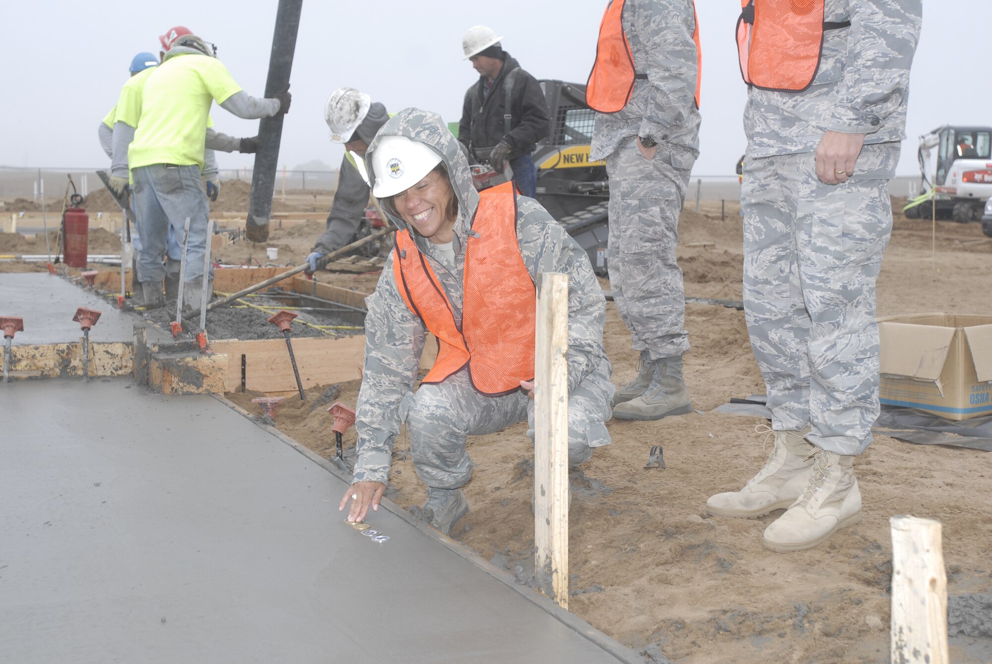 Col. Emily Buckman, 21st Mission Support Group commander, places the official 21st MSG coin into the first new Tierra Vista Communities home foundation on Peterson Air Force Base, Oct. 20. This foundation pouring marked the beginning of phase one of new construction on the privatized housing development. This initial phase will include 93 homes. (Air Force photo/Larry Hulst)
